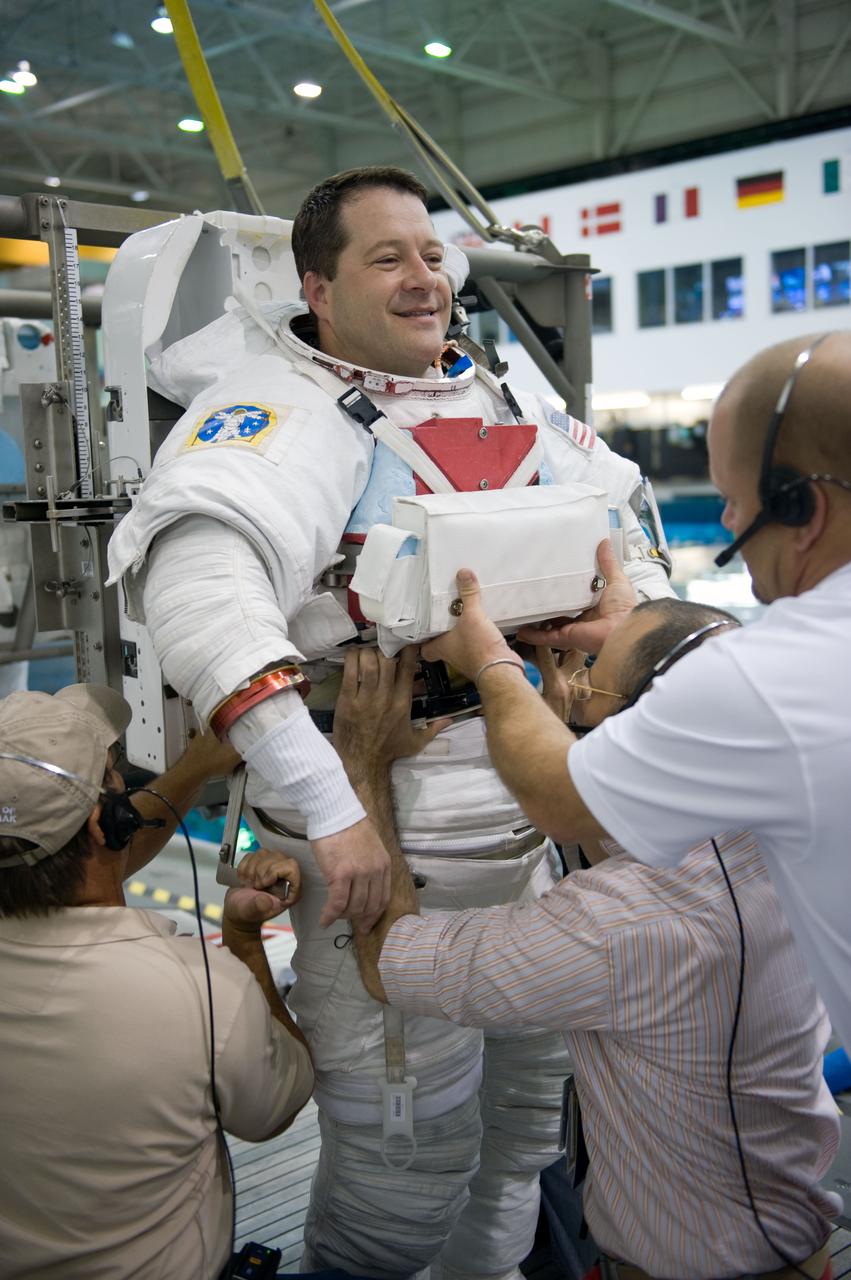 JSC2009-E-145705 (17 July 2009) --- Astronaut Nicholas Patrick, STS-130 mission specialist, gets help in the donning of a training version of his Extravehicular Mobility Unit (EMU) spacesuit in preparation for a spacewalk training session in the waters of the Neutral Buoyancy Laboratory (NBL) near NASA's Johnson Space Center.