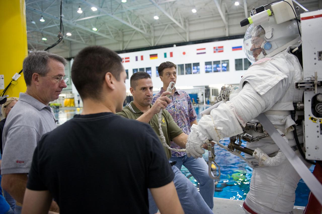 JSC2009-E-145709 (17 July 2009) --- Astronaut Robert Behnken, STS-130 mission specialist, attired in a training version of his Extravehicular Mobility Unit (EMU) spacesuit, prepares for a spacewalk training session in the waters of the Neutral Buoyancy Laboratory (NBL) near NASA's Johnson Space Center. Astronaut George Zamka (center), commander, assisted Behnken. Astronaut Stephen Robinson, mission specialist, is at left.