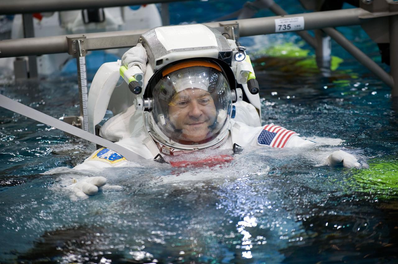 JSC2009-E-145718 (17 July 2009) --- Astronaut Nicholas Patrick, STS-130 mission specialist, attired in a training version of his Extravehicular Mobility Unit (EMU) spacesuit, is submerged in the waters of the Neutral Buoyancy Laboratory (NBL) near NASA's Johnson Space Center. SCUBA-equipped divers (out of frame) are in the water to assist Patrick in his rehearsal, intended to help prepare him for work on the exterior of the International Space Station.