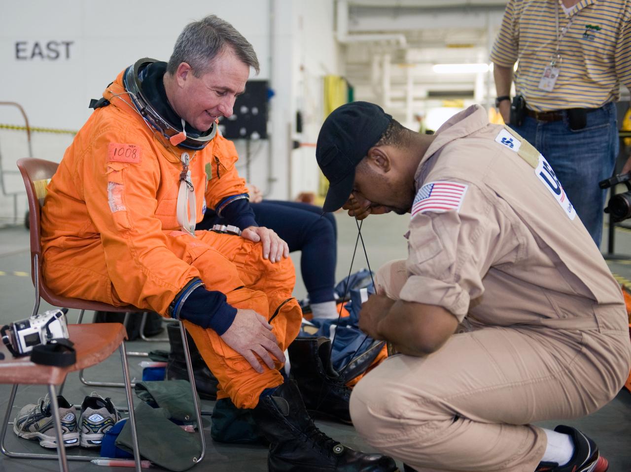 JSC2009-E-155133 (24 Aug. 2009) --- Astronaut Stephen Robinson, STS-130 mission specialist, gets help with the donning of a training version of his shuttle launch and entry suit in preparation for a water survival training session in the waters of the Neutral Buoyancy Laboratory (NBL) near NASA's Johnson Space Center.