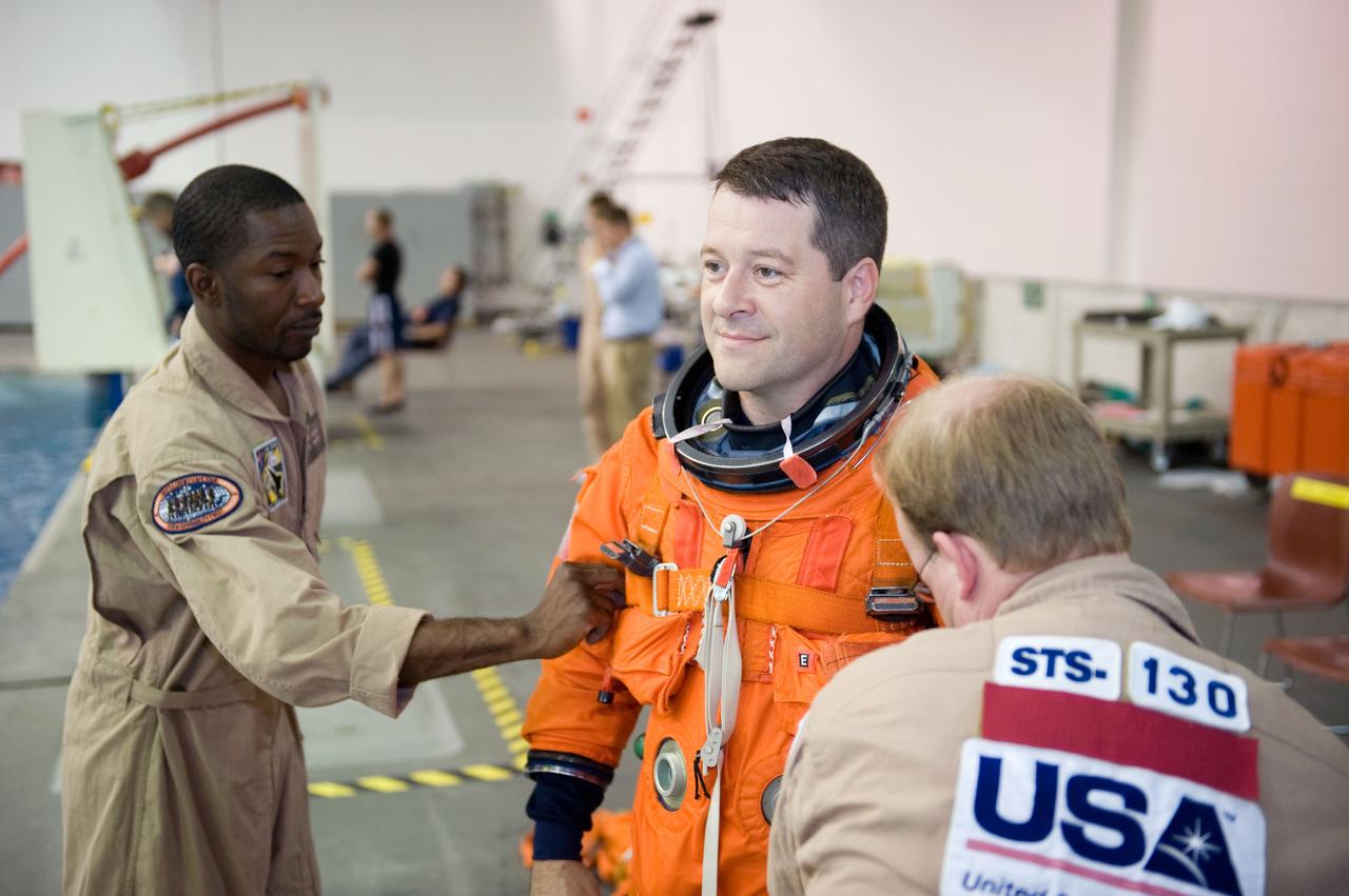 JSC2009-E-155149 (24 Aug. 2009) --- Astronaut Nicholas Patrick, STS-130 mission specialist, gets help with the donning of a training version of his shuttle launch and entry suit in preparation for a water survival training session in the waters of the Neutral Buoyancy Laboratory (NBL) near NASA's Johnson Space Center.