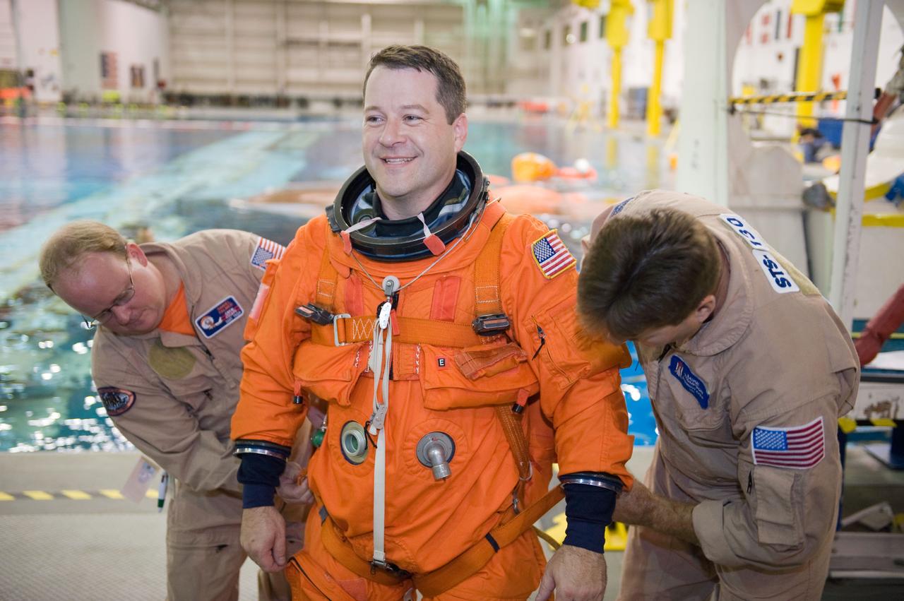 JSC2009-E-155150 (24 Aug. 2009) --- Astronaut Nicholas Patrick, STS-130 mission specialist, dons a training version of his shuttle launch and entry suit in preparation for a water survival training session in the waters of the Neutral Buoyancy Laboratory (NBL) near NASA's Johnson Space Center. United Space Alliance suit technicians Daniel Palmer (left) and Mike Thompson assisted Patrick.