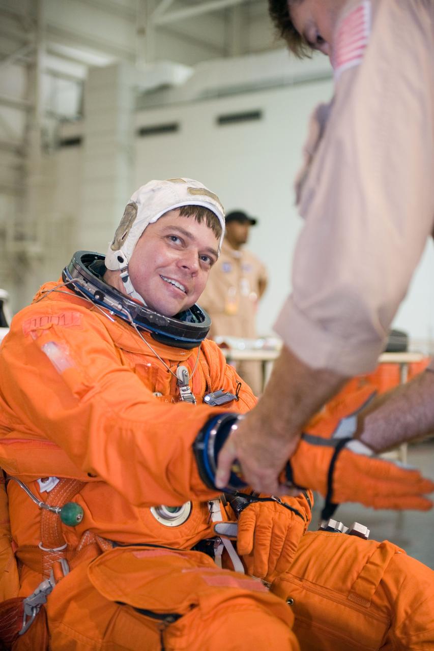JSC2009-E-155160 (24 Aug. 2009) --- Astronaut Robert Behnken, STS-130 mission specialist, dons a training version of his shuttle launch and entry suit in preparation for a water survival training session in the waters of the Neutral Buoyancy Laboratory (NBL) near NASA's Johnson Space Center. United Space Alliance suit technician Mike Thompson assisted Behnken.