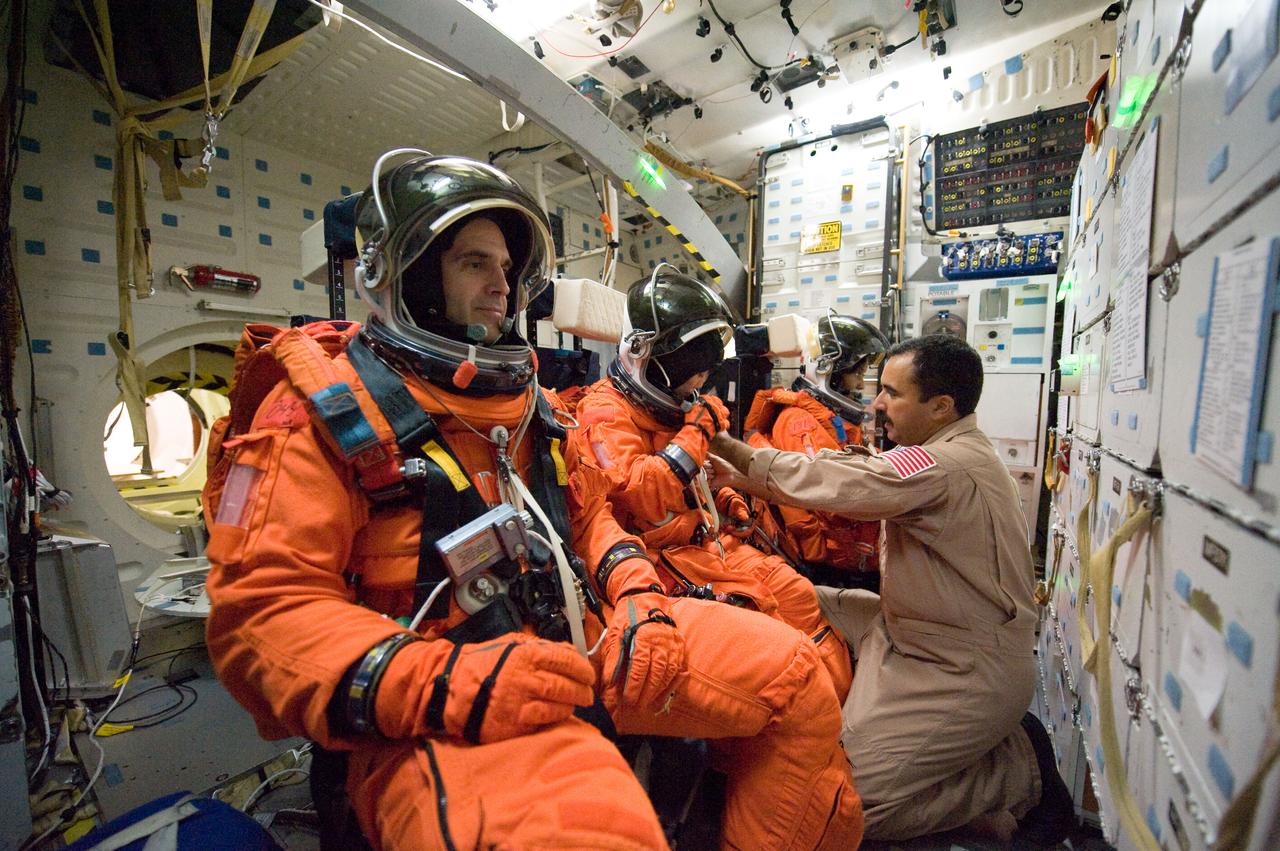 JSC2009-E-207964 (14 Sept. 2009) --- NASA astronaut Rick Mastracchio (foreground), Japan Aerospace Exploration Agency (JAXA) astronaut Naoko Yamazaki and NASA astronaut Stephanie Wilson, all STS-131 mission specialists, participate in a training session in one of the full-scale trainers in the Space Vehicle Mock-up Facility at NASA's Johnson Space Center. Attired in training versions of their shuttle launch and entry suits, the three are seated on the middeck for a post insertion/de-orbit training session. United Space Alliance suit technician Raymond Cuevas assisted the crew members.