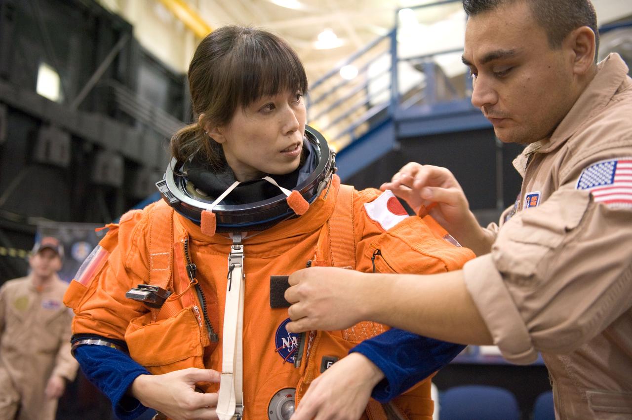 JSC2009-E-208020 (14 Sept. 2009) --- Japan Aerospace Exploration Agency (JAXA) astronaut Naoko Yamazaki, STS-131 mission specialist, dons a training version of her shuttle launch and entry suit in preparation for a training session in the Space Vehicle Mock-up Facility at NASA's Johnson Space Center. United Space Alliance suit technician Russ Baker assisted Yamazaki.