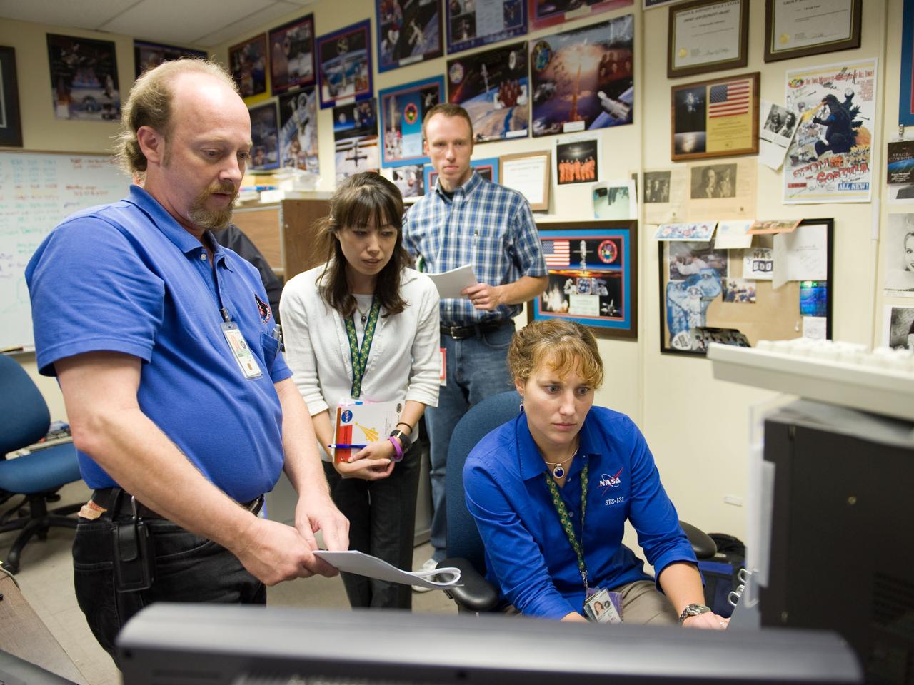 JSC2009-E-214320 (25 Sept. 2009) --- NASA astronaut Dorothy Metcalf-Lindenburger (seated) and Japan Aerospace Exploration Agency (JAXA) astronaut Naoko Yamazaki, both STS-131 mission specialists, use the virtual reality lab in the Space Vehicle Mock-up Facility at NASA's Johnson Space Center to train for some of their duties aboard the space shuttle and space station. This type of computer interface, paired with virtual reality training hardware and software, helps to prepare the entire team for dealing with space station elements. United Space Alliance crew instructor Stephan Kinstle (left) assisted the crew members.
