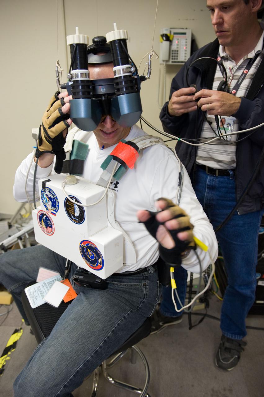 JSC2009-E-214334 (25 Sept. 2009) --- NASA astronaut Clayton Anderson, STS-131 mission specialist, uses virtual reality hardware in the Space Vehicle Mock-up Facility at NASA's Johnson Space Center to rehearse some of his duties on the upcoming mission to the International Space Station. This type of virtual reality training allows the astronauts to wear a helmet and special gloves while looking at computer displays simulating actual movements around the various locations on the station hardware with which they will be working. Crew instructor Bradley Bell assisted Anderson.