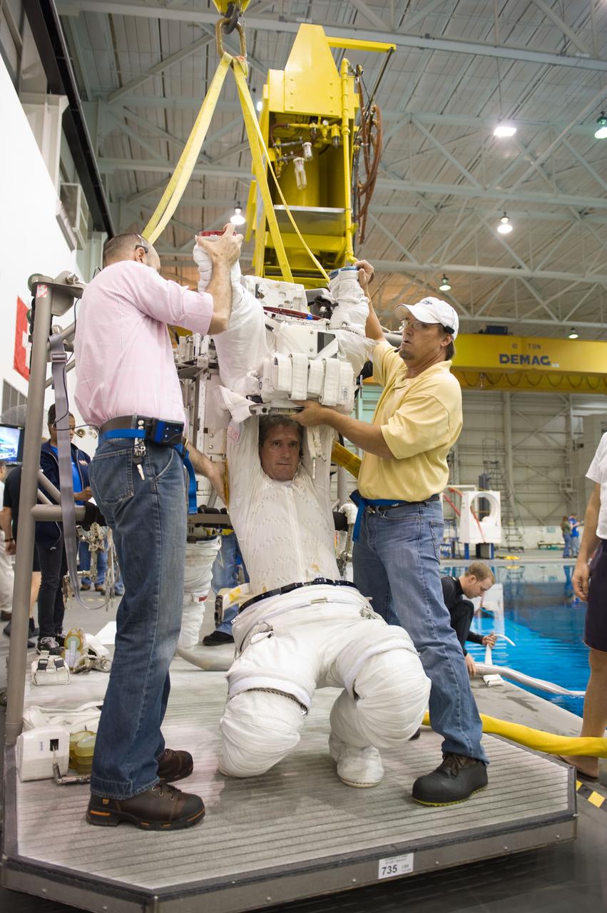 JSC2009-E-215149 (30 Sept. 2009) --- Astronaut Mike Good, STS-132 mission specialist, gets help in the donning of a training version of his Extravehicular Mobility Unit (EMU) spacesuit in preparation for a spacewalk training session in the waters of the Neutral Buoyancy Laboratory (NBL) near NASA's Johnson Space Center.