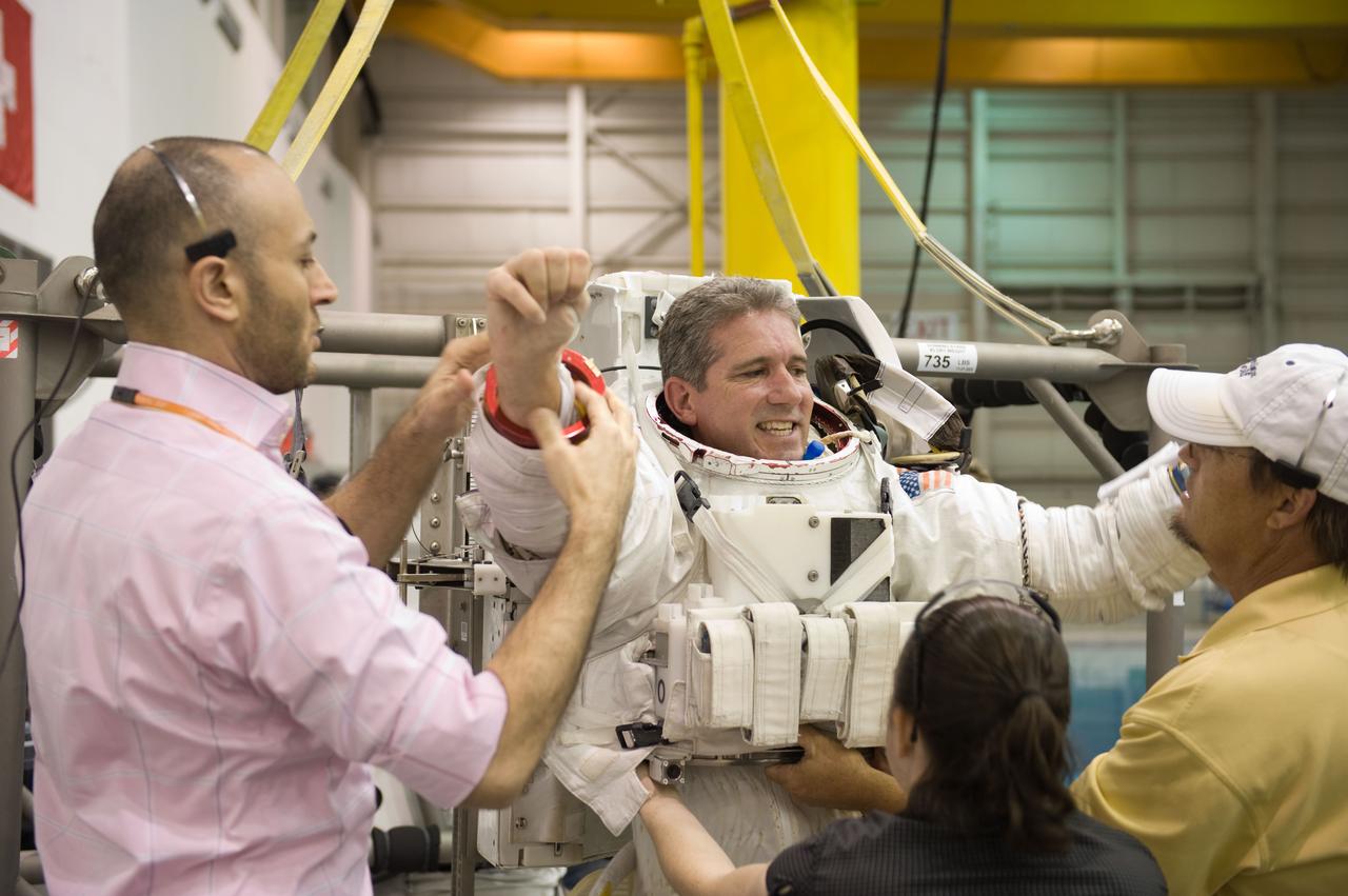 JSC2009-E-215150 (30 Sept. 2009) --- Astronaut Mike Good, STS-132 mission specialist, gets help in the donning of a training version of his Extravehicular Mobility Unit (EMU) spacesuit in preparation for a spacewalk training session in the waters of the Neutral Buoyancy Laboratory (NBL) near NASA's Johnson Space Center.