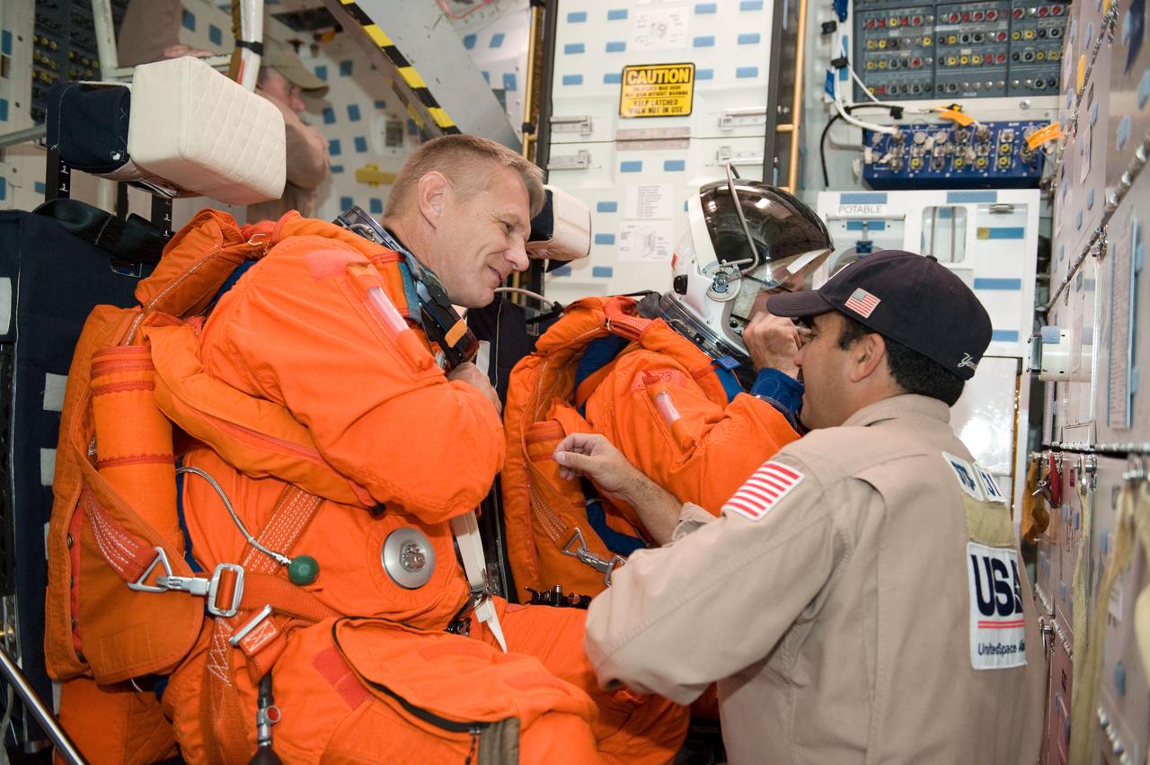 JSC2009-E-224139 (20 Oct. 2009) --- Astronauts Piers Sellers (left) and Steve Bowen, both STS-132 mission specialists, participate in a training session in one of the full-scale trainers in the Space Vehicle Mock-up Facility at NASA's Johnson Space Center. Attired in training versions of their shuttle launch and entry suits, the two are seated on the middeck for a post insertion/de-orbit training session. United Space Alliance suit technician Raymond Cuevas (right) assisted the crew members.