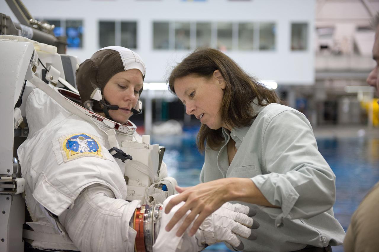 JSC2009-E-226227 (28 Oct. 2009) --- Astronaut Tracy Caldwell, Expedition 23/24 flight engineer, dons a training version of her Extravehicular Mobility Unit (EMU) spacesuit in preparation for a spacewalk training session in the waters of the Neutral Buoyancy Laboratory (NBL) near NASA's Johnson Space Center. Astronaut Shannon Walker, Expedition 24/25 flight engineer, assisted Caldwell.