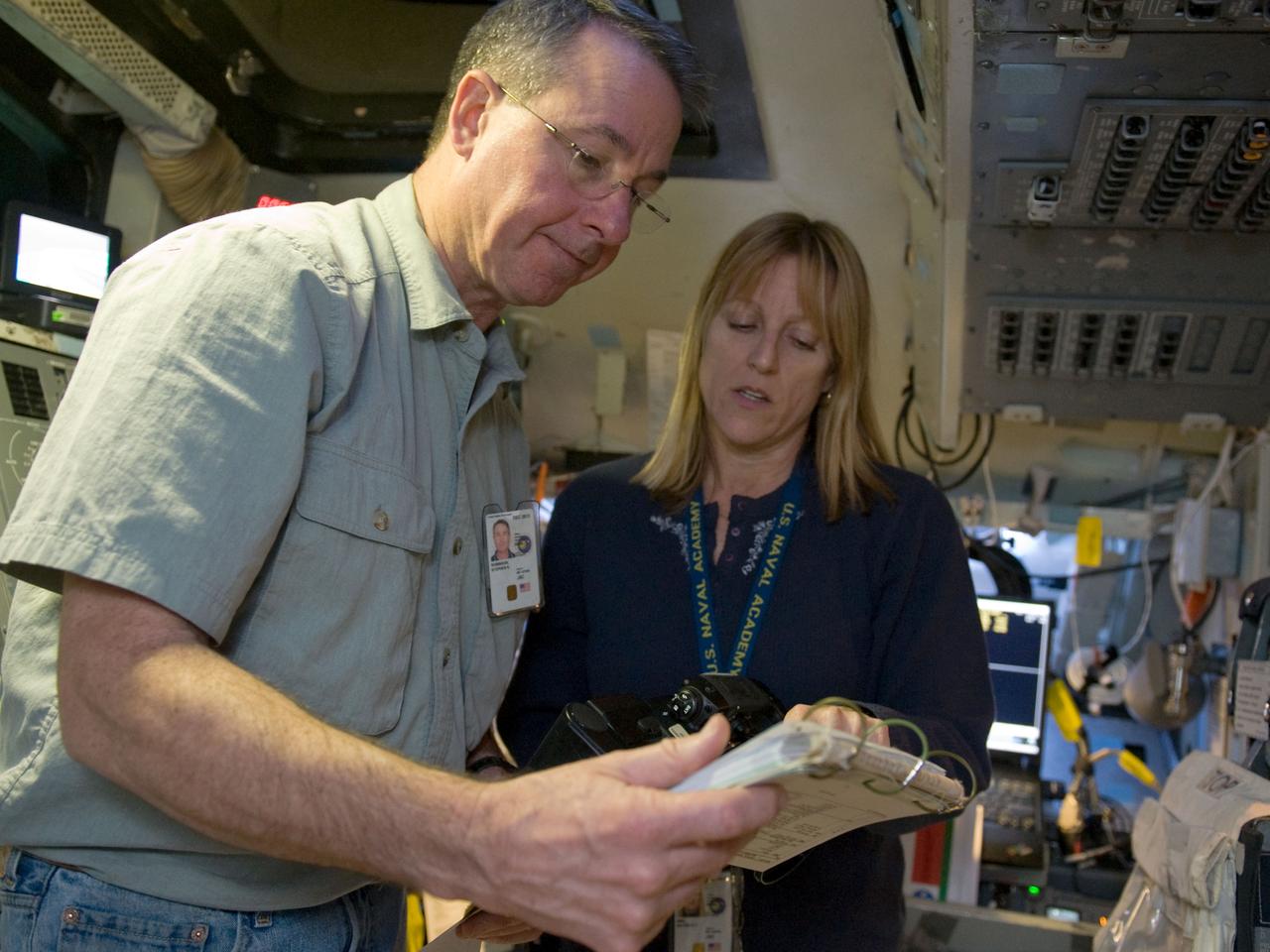 JSC2009-E-240765 (12 Nov. 2009) --- Astronauts Stephen Robinson and Kathryn Hire, both STS-130 mission specialists, read a procedure checklist during a training session in a fixed-base shuttle mission simulator (SMS) training session in the Jake Garn Simulation and Training Facility at NASA's Johnson Space Center.