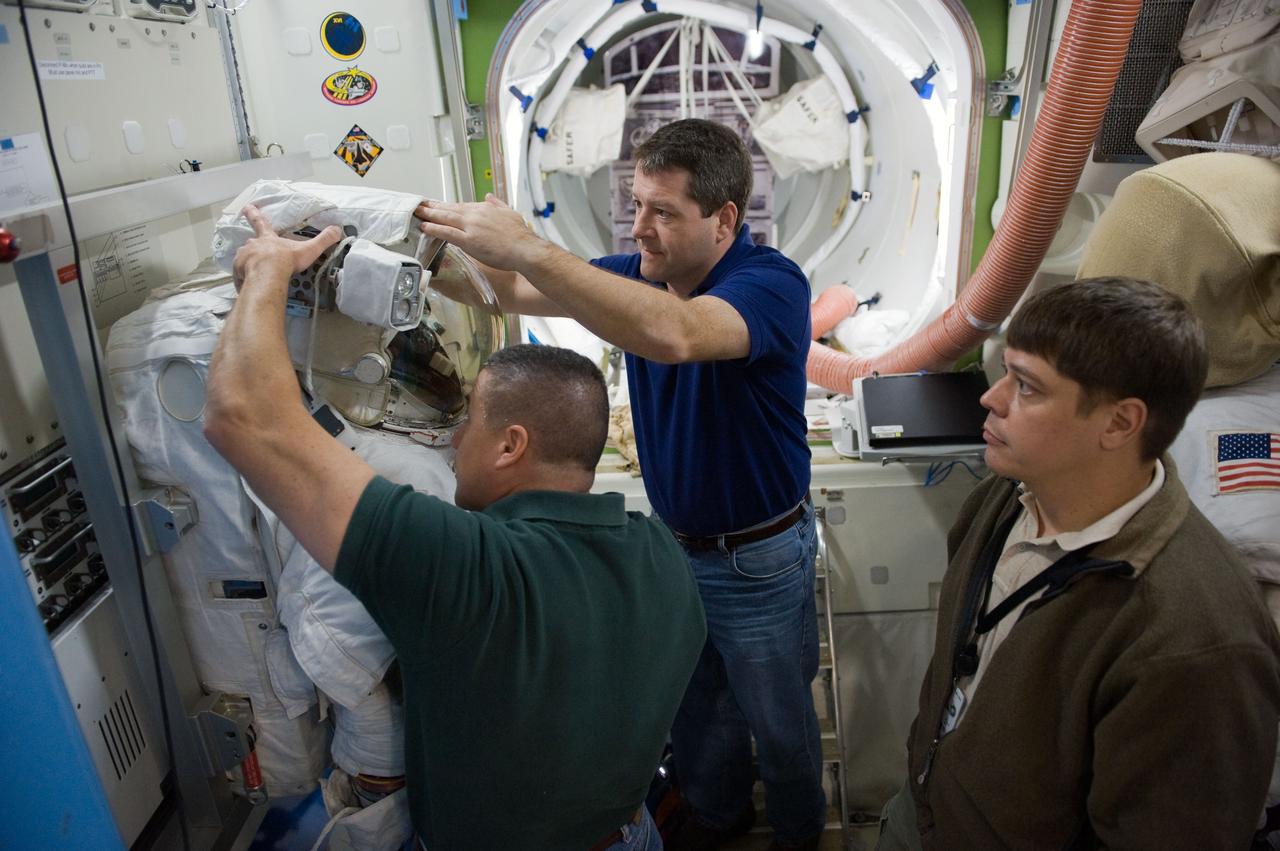 JSC2009-E-244236 (23 Nov. 2009) --- Astronaut George Zamka (left foreground), STS-130 commander; and astronaut Nicholas Patrick, mission specialist, work with an Extravehicular Mobility Unit (EMU) spacesuit during a training session in an International Space Station mock-up/trainer in the Space Vehicle Mock-up Facility at NASA's Johnson Space Center. Astronaut Robert Behnken, mission specialist, is at right.