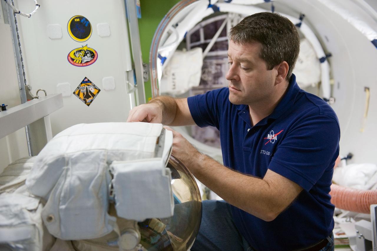 JSC2009-E-244240 (23 Nov. 2009) --- Astronaut Nicholas Patrick, STS-130 mission specialist, works with an Extravehicular Mobility Unit (EMU) spacesuit during a training session in an International Space Station mock-up/trainer in the Space Vehicle Mock-up Facility at NASA's Johnson Space Center.