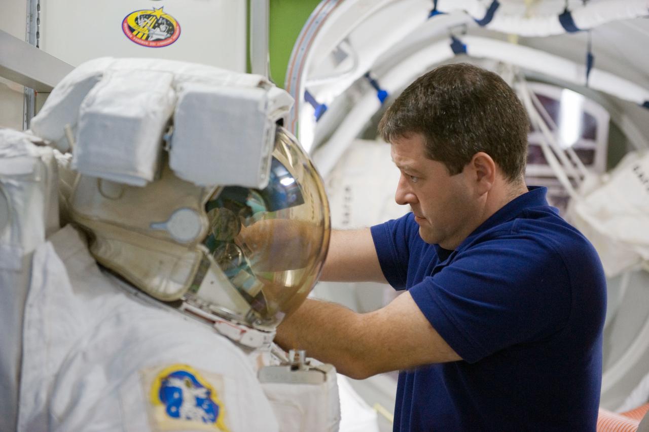 JSC2009-E-244245 (23 Nov. 2009) --- Astronaut Nicholas Patrick, STS-130 mission specialist, works with an Extravehicular Mobility Unit (EMU) spacesuit during a training session in an International Space Station mock-up/trainer in the Space Vehicle Mock-up Facility at NASA's Johnson Space Center.