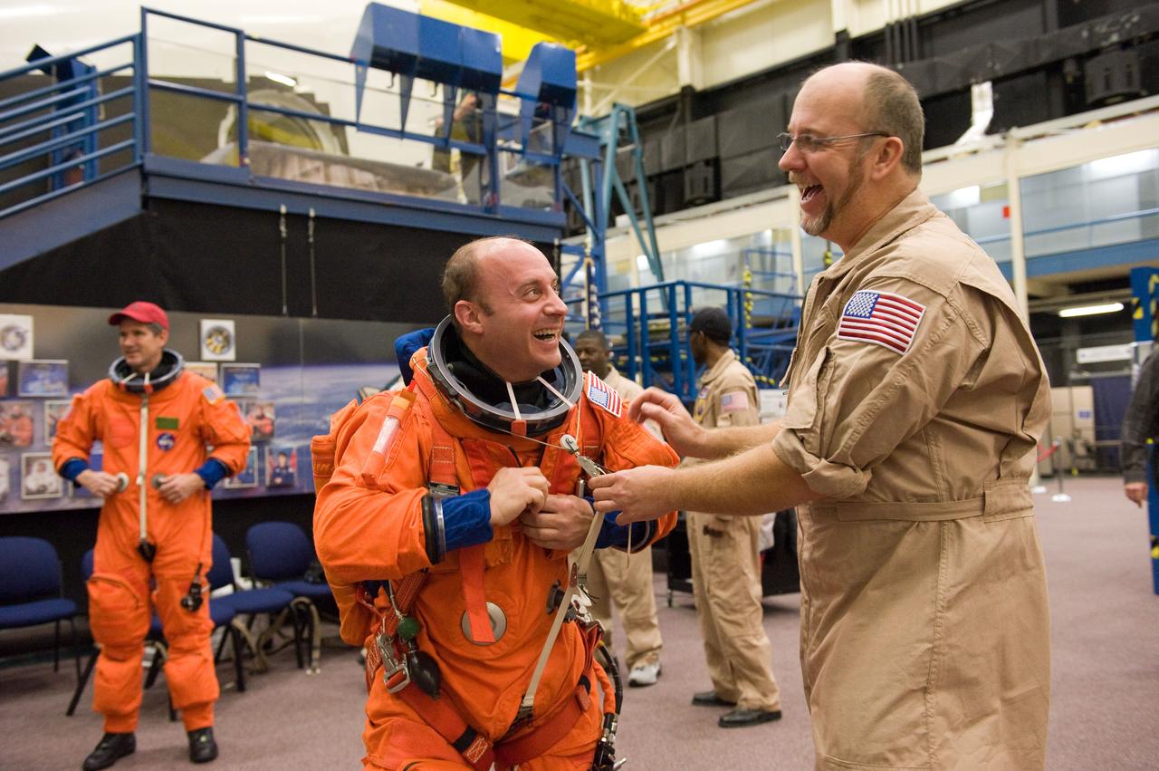 JSC2009-E-258456 (8 Dec. 2009) --- Astronaut Garrett Reisman, STS-132 mission specialist, dons a training version of his shuttle launch and entry suit in preparation for a training session in the Space Vehicle Mock-up Facility at NASA's Johnson Space Center. United Space Alliance suit technician Steve Sholtz assisted Reisman.