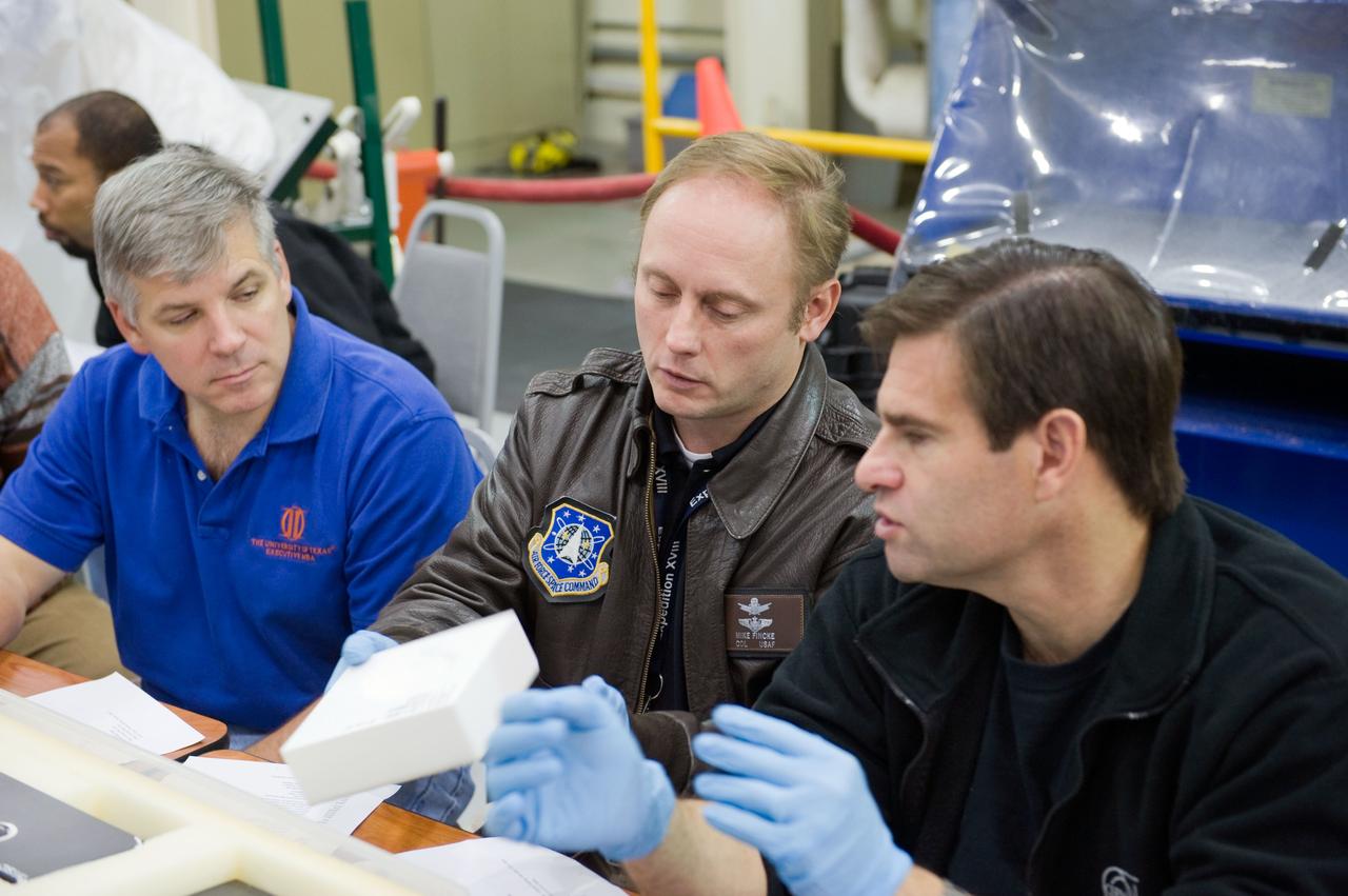 JSC2009-E-284896 (15 Dec. 2009) --- NASA astronauts Gregory H. Johnson (left), STS-134 pilot; along with astronauts Michael Fincke (center) and Greg Chamitoff, both mission specialists, participate in an EVA Thermal Protection System (TPS) overview training session in the TPS/ Precision Air Bearing Facility in the Space Vehicle Mock-up Facility at NASA?s Johnson Space Center.