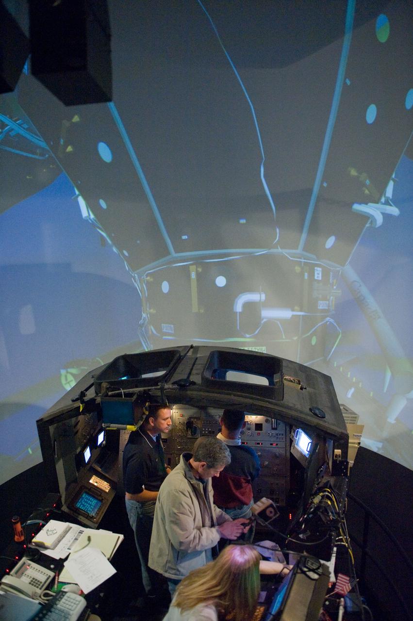JSC2009-E-286974 (22 Dec. 2009) --- Astronauts Ken Ham (left background), STS-132 commander; Tony Antonelli (right background), pilot; and Mike Good, mission specialist, participate in an exercise in the systems engineering simulator in the Avionics Systems Laboratory at NASA?s Johnson Space Center. The facility includes moving scenes of full-sized International Space Station components over a simulated Earth.