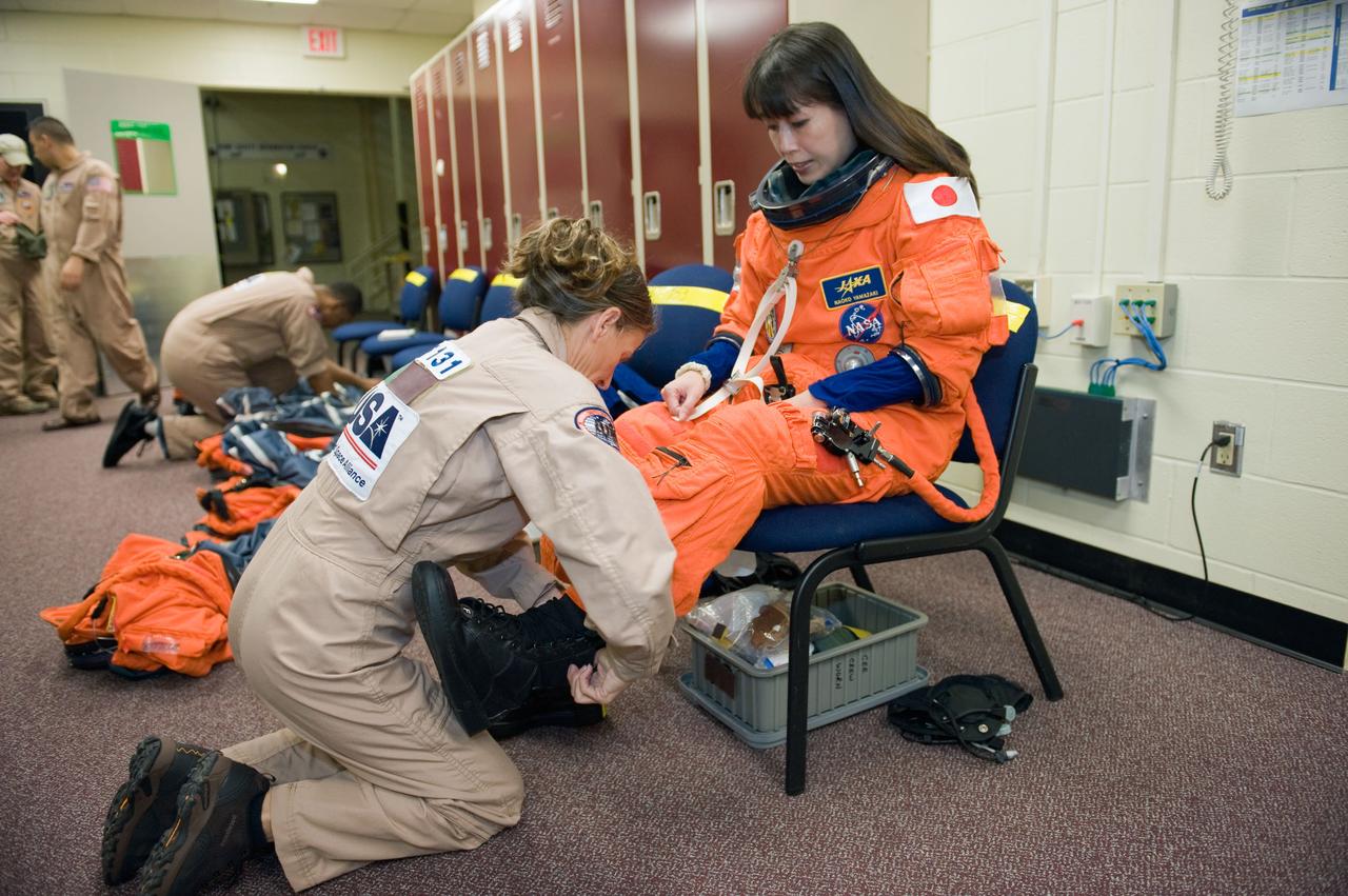 JSC2009-E-287959 (9 Dec. 2009) --- Japan Aerospace Exploration Agency (JAXA) astronaut Naoko Yamazaki, STS-131 mission specialist, dons a training version of her shuttle launch and entry suit in preparation for a training session in the Space Vehicle Mock-up Facility at NASA's Johnson Space Center. United Space Alliance suit technician Toni Cost-Davis assisted Yamazaki.