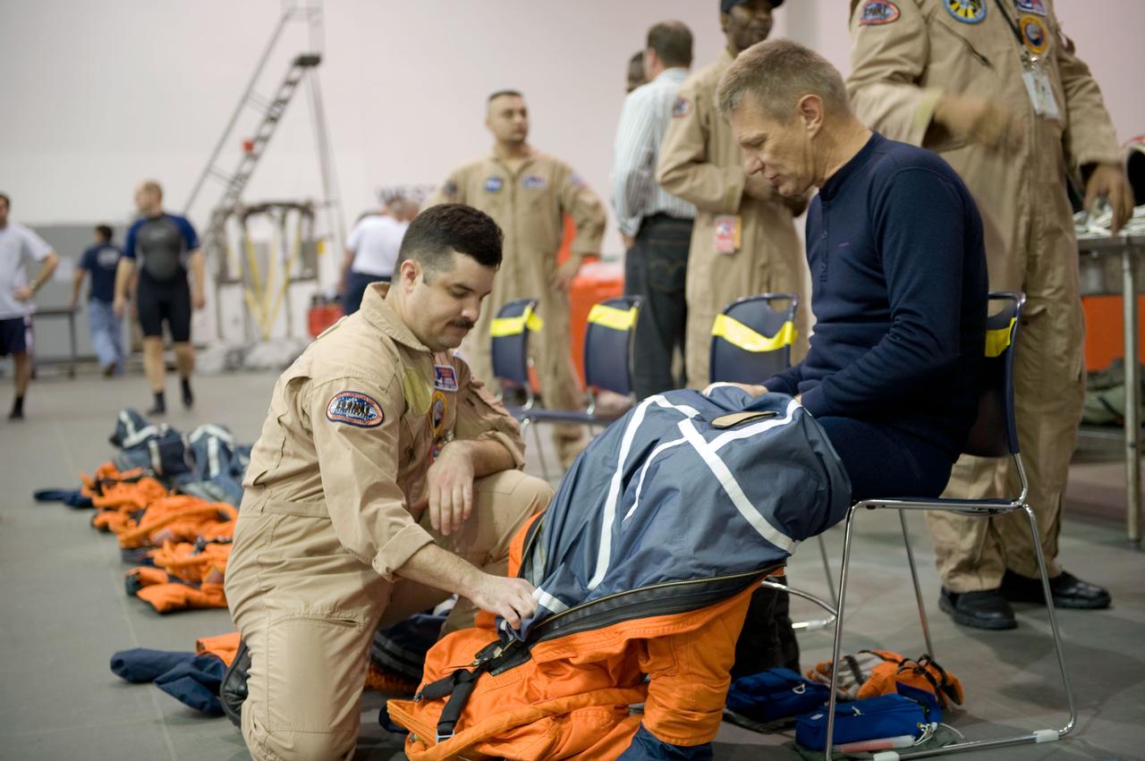 JSC2010-E-013684 (20 Jan. 2010) --- Astronaut Piers Sellers, STS-132 mission specialist, dons a training version of his shuttle launch and entry suit in preparation for a water survival training session in the Neutral Buoyancy Laboratory (NBL) near NASA's Johnson Space Center. United Space Alliance suit technician Carlos Ramos assisted Sellers.