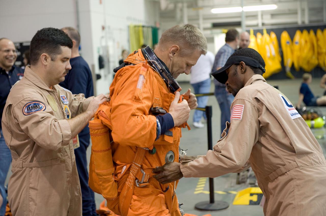 JSC2010-E-013685 (20 Jan. 2010) --- Astronaut Piers Sellers, STS-132 mission specialist, gets help with the donning of a training version of his shuttle launch and entry suit in preparation for a water survival training session in the Neutral Buoyancy Laboratory (NBL) near NASA's Johnson Space Center.