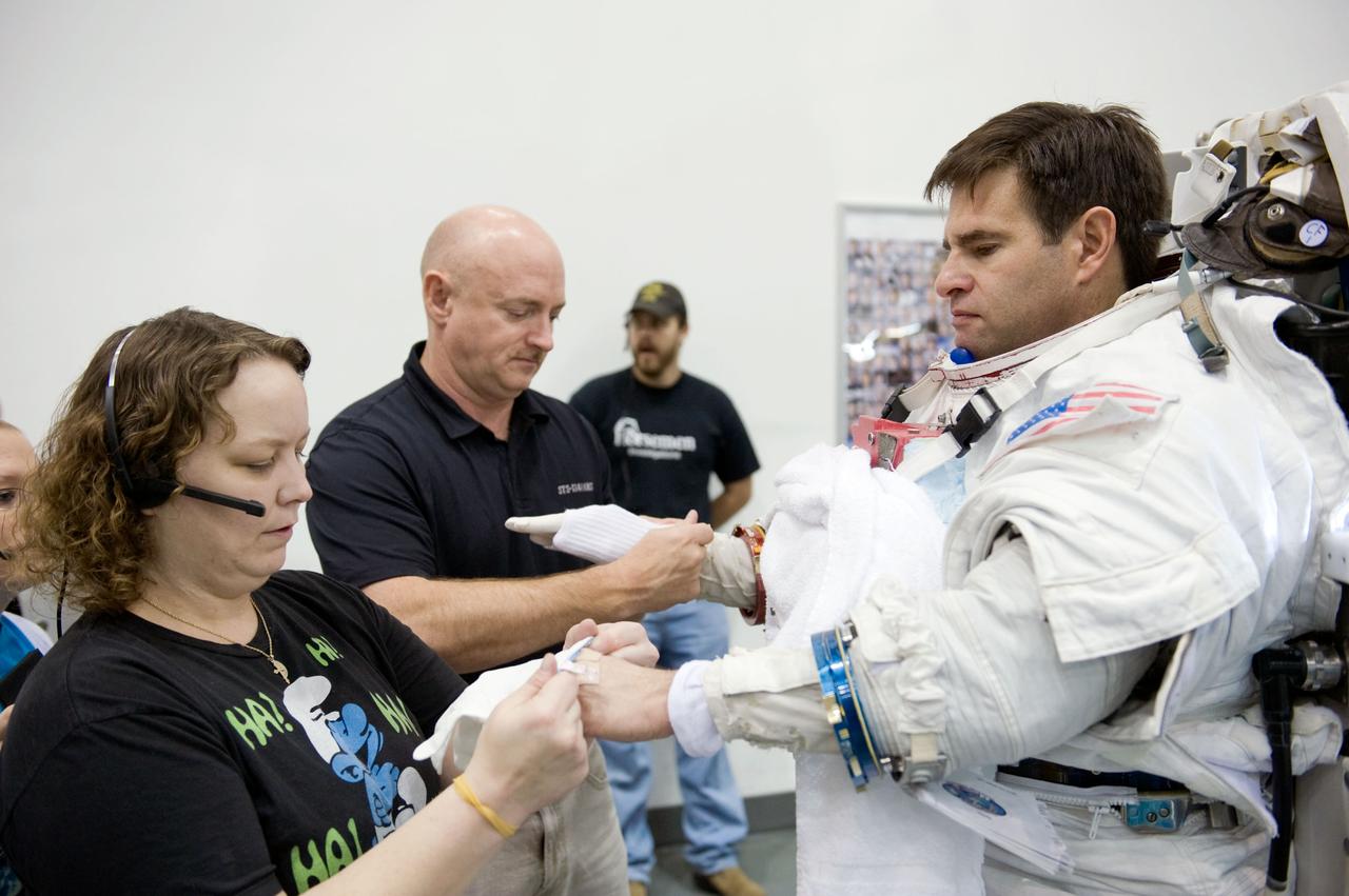 JSC2010-E-014278 (27 Jan. 2010) --- NASA astronaut Greg Chamitoff, STS-134 mission specialist, gets help in the donning of a training version of his Extravehicular Mobility Unit (EMU) spacesuit in preparation for a spacewalk training session in the waters of the Neutral Buoyancy Laboratory (NBL) near NASA's Johnson Space Center. Astronaut Mark Kelly, commander, assisted Chamitoff.