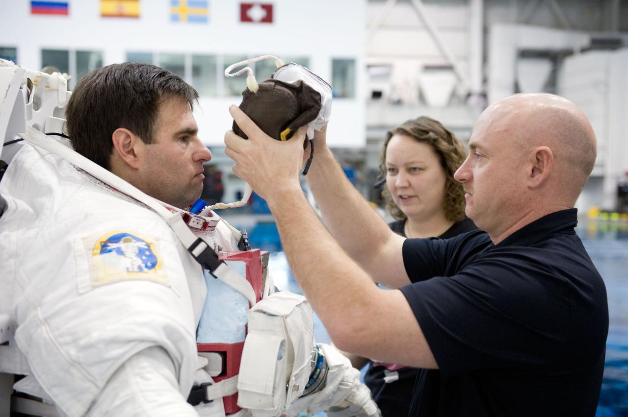 JSC2010-E-014281 (27 Jan. 2010) --- NASA astronaut Greg Chamitoff, STS-134 mission specialist, gets help in the donning of a training version of his Extravehicular Mobility Unit (EMU) spacesuit in preparation for a spacewalk training session in the waters of the Neutral Buoyancy Laboratory (NBL) near NASA's Johnson Space Center. Astronaut Mark Kelly, commander, assisted Chamitoff.