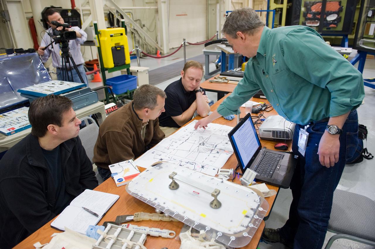 JSC2010-E-014772 (28 Jan. 2010) --- NASA astronauts Greg Chamitoff (left), Andrew Feustel and Michael Fincke, all STS-134 mission specialists, participate in an EVA tile repair training session in the Space Vehicle Mock-up Facility at NASA's Johnson Space Center. Instructor John Ray (right) assisted the crew members.