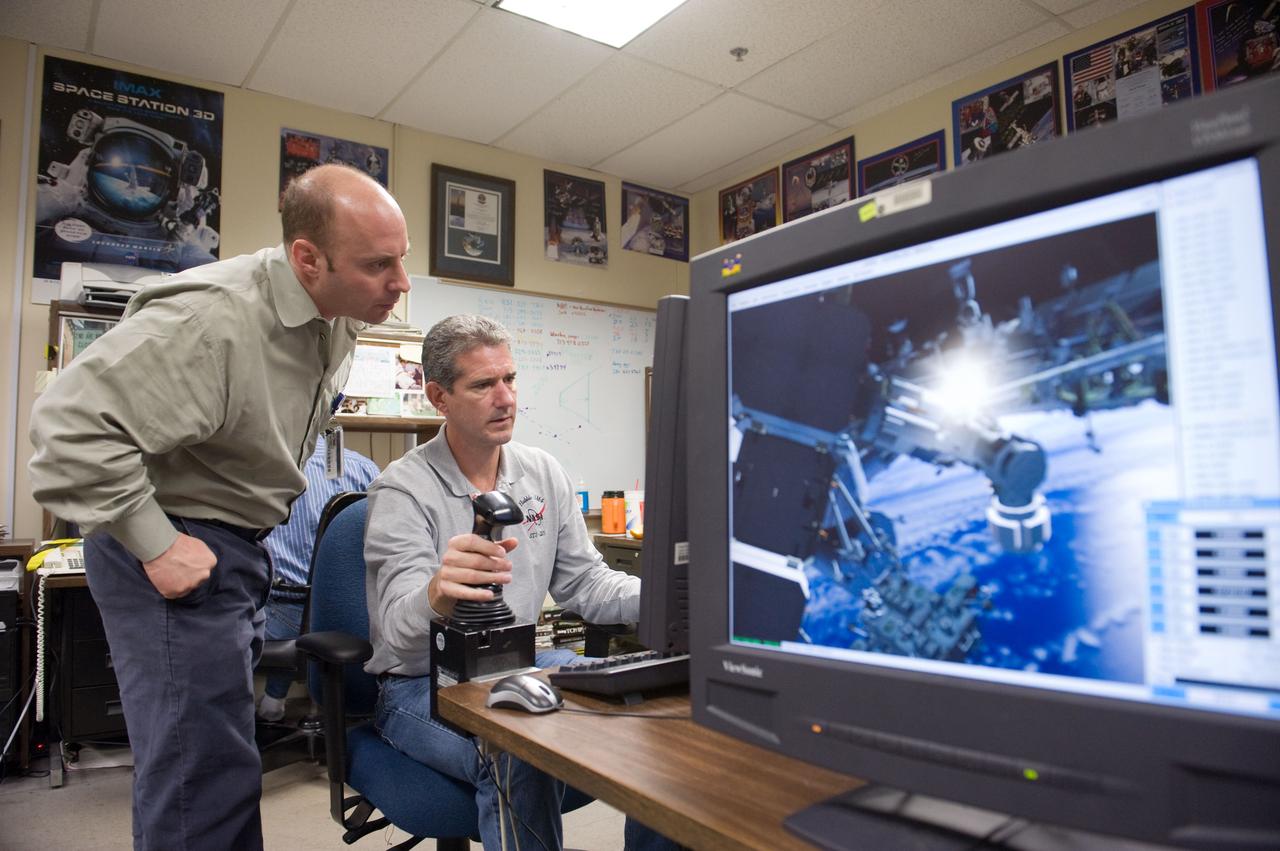 JSC2010-E-014952 (28 Jan. 2010) --- NASA astronauts Michael Good (seated) and Garrett Reisman, both STS-132 mission specialists, use the virtual reality lab in the Space Vehicle Mock-up Facility at NASA's Johnson Space Center to train for some of their duties aboard the space shuttle and space station. This type of computer interface, paired with virtual reality training hardware and software, helps to prepare crew members for dealing with space station elements.