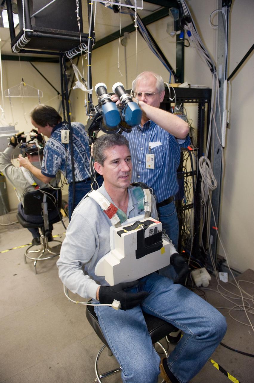 JSC2010-E-014957 (28 Jan. 2010) --- NASA astronaut Michael Good, STS-132 mission specialist, uses virtual reality hardware in the Space Vehicle Mock-up Facility at NASA's Johnson Space Center to rehearse some of his duties on the upcoming mission to the International Space Station. This type of virtual reality training allows the astronauts to wear a helmet and special gloves while looking at computer displays simulating actual movements around the various locations on the station hardware with which they will be working. David Homan assisted Good.