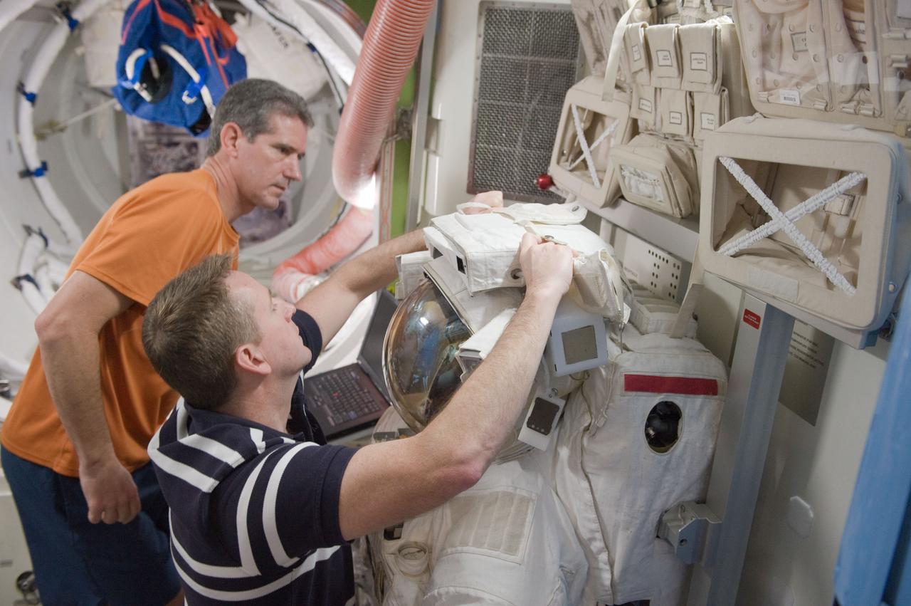 JSC2010-E-015332 (27 Jan. 2010) --- NASA astronauts Ken Ham (foreground), STS-132 commander; and Michael Good, mission specialist, work with an Extravehicular Mobility Unit (EMU) spacesuit during a training session in an International Space Station mock-up/trainer in the Space Vehicle Mock-up Facility at NASA's Johnson Space Center.