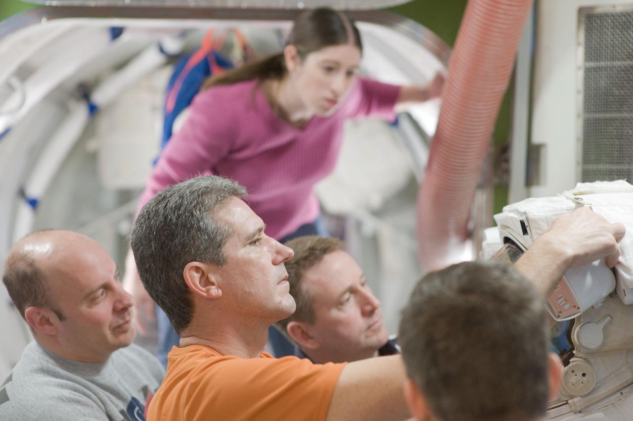 JSC2010-E-015333 (27 Jan. 2010) --- STS-132 crew members work with an Extravehicular Mobility Unit (EMU) spacesuit during a training session in an International Space Station mock-up/trainer in the Space Vehicle Mock-up Facility at NASA's Johnson Space Center. Pictured are NASA astronaut Ken Ham (center background), commander; along with astronauts Garrett Reisman (left), Michael Good and Steve Bowen (mostly out of frame at right), all mission specialists.