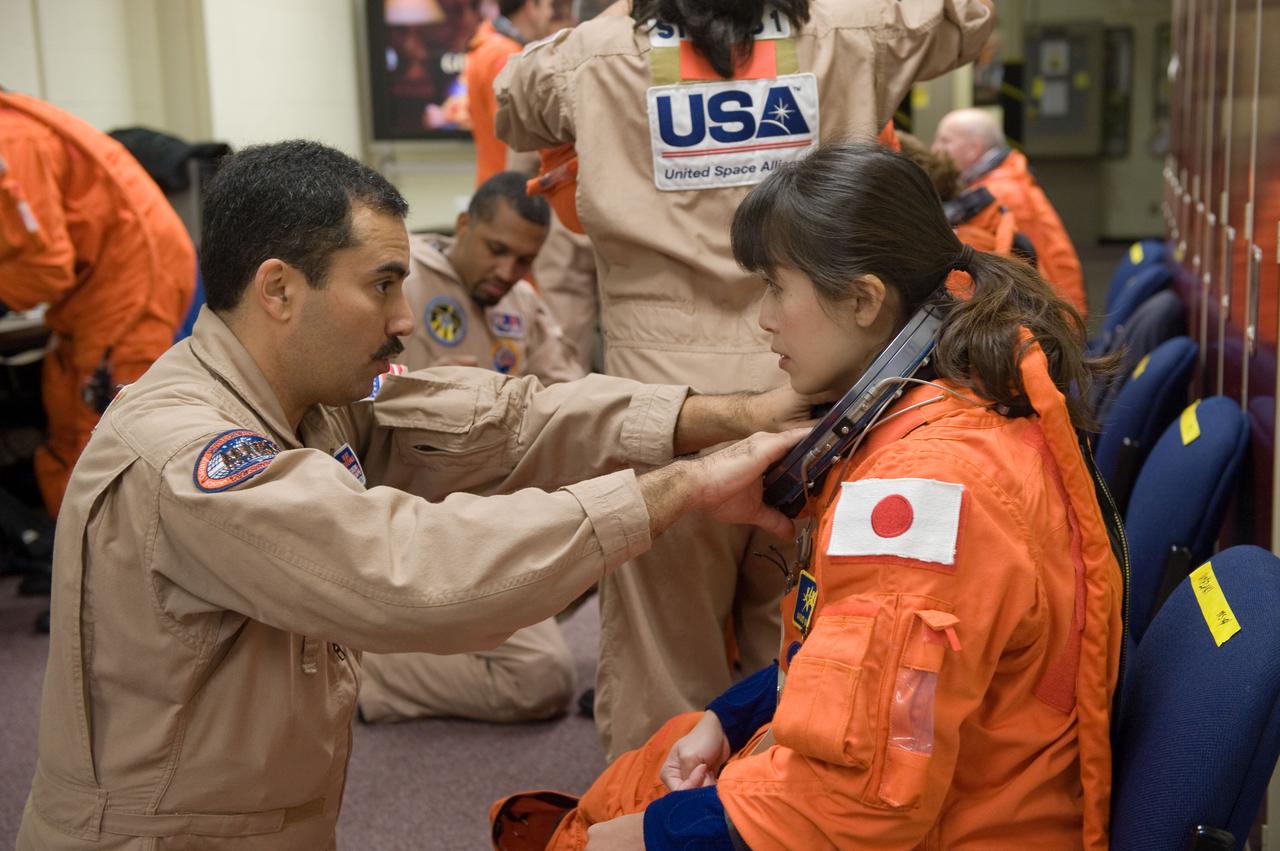 JSC2010-E-017720 (29 Jan. 2010) --- Japan Aerospace Exploration Agency (JAXA) astronaut Naoko Yamazaki, STS-131 mission specialist, dons a training version of her shuttle launch and entry suit in preparation for an ingress/egress training session in the Space Vehicle Mock-up Facility at NASA's Johnson Space Center. United Space Alliance suit technician Raymond Cuevas assisted Yamazaki.