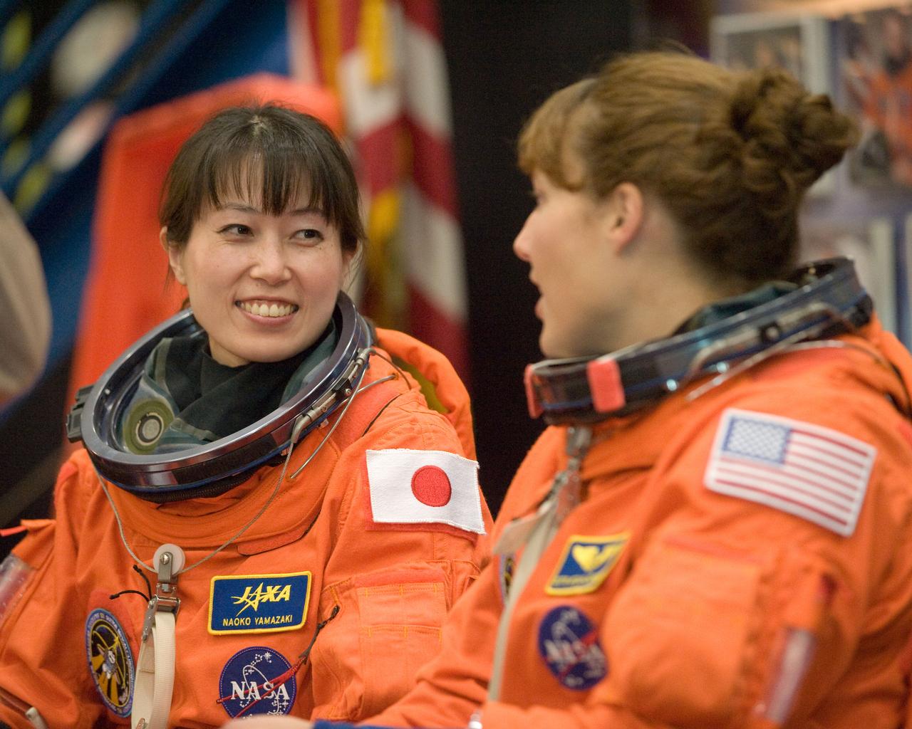 JSC2010-E-017732 (29 Jan. 2010) --- Japan Aerospace Exploration Agency (JAXA) astronaut Naoko Yamazaki (left) and NASA astronaut Dorothy Metcalf-Lindenburger, both STS-131 mission specialists, attired in training versions of their shuttle launch and entry suits, await the start of an ingress/egress training session in the Space Vehicle Mock-up Facility at NASA's Johnson Space Center.