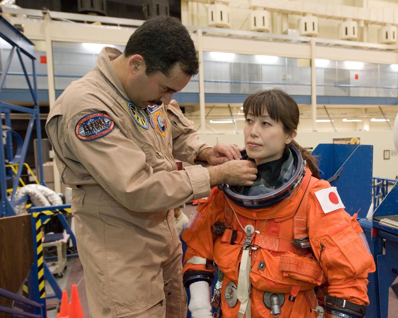 JSC2010-E-017745 (29 Jan. 2010) --- Japan Aerospace Exploration Agency (JAXA) astronaut Naoko Yamazaki, STS-131 mission specialist, dons a training version of her shuttle launch and entry suit in preparation for an ingress/egress training session in the Space Vehicle Mock-up Facility at NASA's Johnson Space Center. United Space Alliance suit technician Raymond Cuevas assisted Yamazaki.