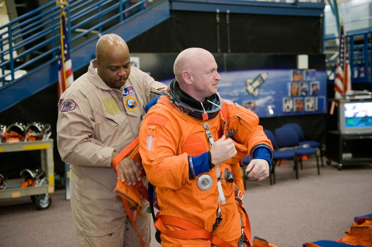 JSC2010-E-018576 (3 Feb. 2010) --- NASA astronaut Mark Kelly, STS-134 commander, dons a training version of his shuttle launch and entry suit in preparation for a training session in the Space Vehicle Mock-up Facility at NASA's Johnson Space Center. United Space Alliance suit technician Andre Denard assisted Kelly.