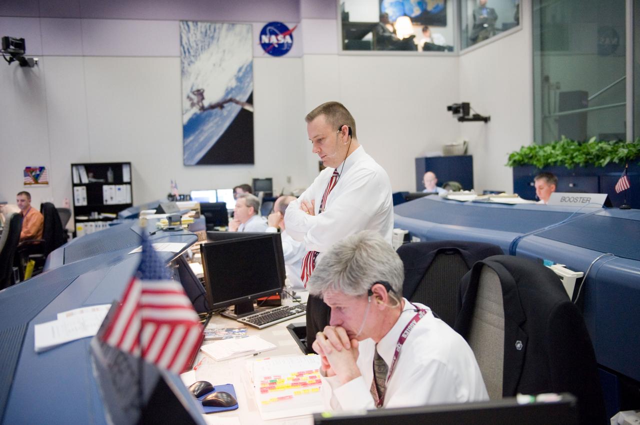 JSC2010-E-018996 (7 Feb. 2010) --- Flight directors Norm Knight (standing) and Bryan Lunney monitor data at their consoles in the space shuttle flight control room in the Johnson Space Center's Mission Control Center during the first launch attempt of the STS-130 mission. The launch was postponed until Feb. 8, due to weather conditions.
