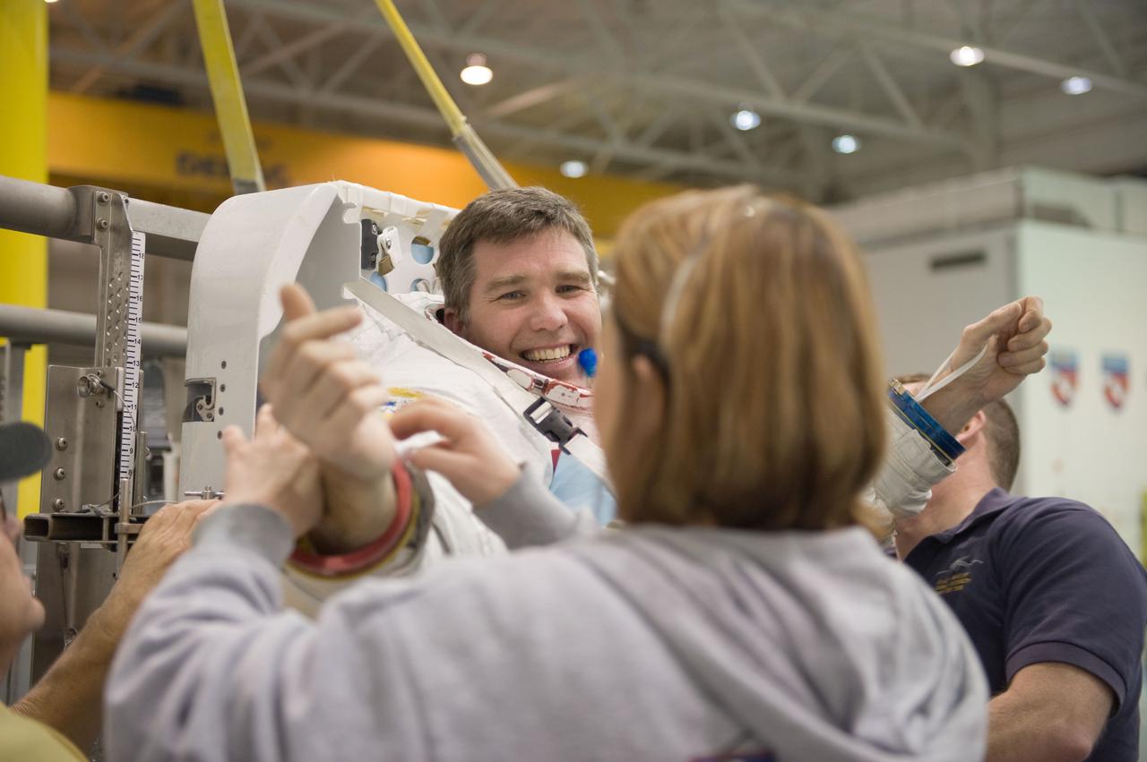 JSC2010-E-019598 (8 Feb. 2010) --- NASA astronaut Steve Bowen, STS-132 mission specialist, gets help in the donning of a training version of his Extravehicular Mobility Unit (EMU) spacesuit in preparation for a spacewalk training session in the waters of the Neutral Buoyancy Laboratory (NBL) near NASA's Johnson Space Center.