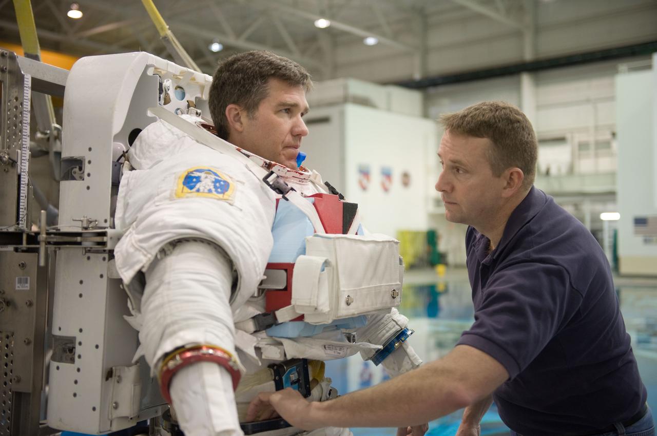 JSC2010-E-019601 (8 Feb. 2010) --- NASA astronaut Steve Bowen, STS-132 mission specialist, dons a training version of his Extravehicular Mobility Unit (EMU) spacesuit in preparation for a spacewalk training session in the waters of the Neutral Buoyancy Laboratory (NBL) near NASA's Johnson Space Center. Astronaut Ken Ham, commander, assisted Bowen.