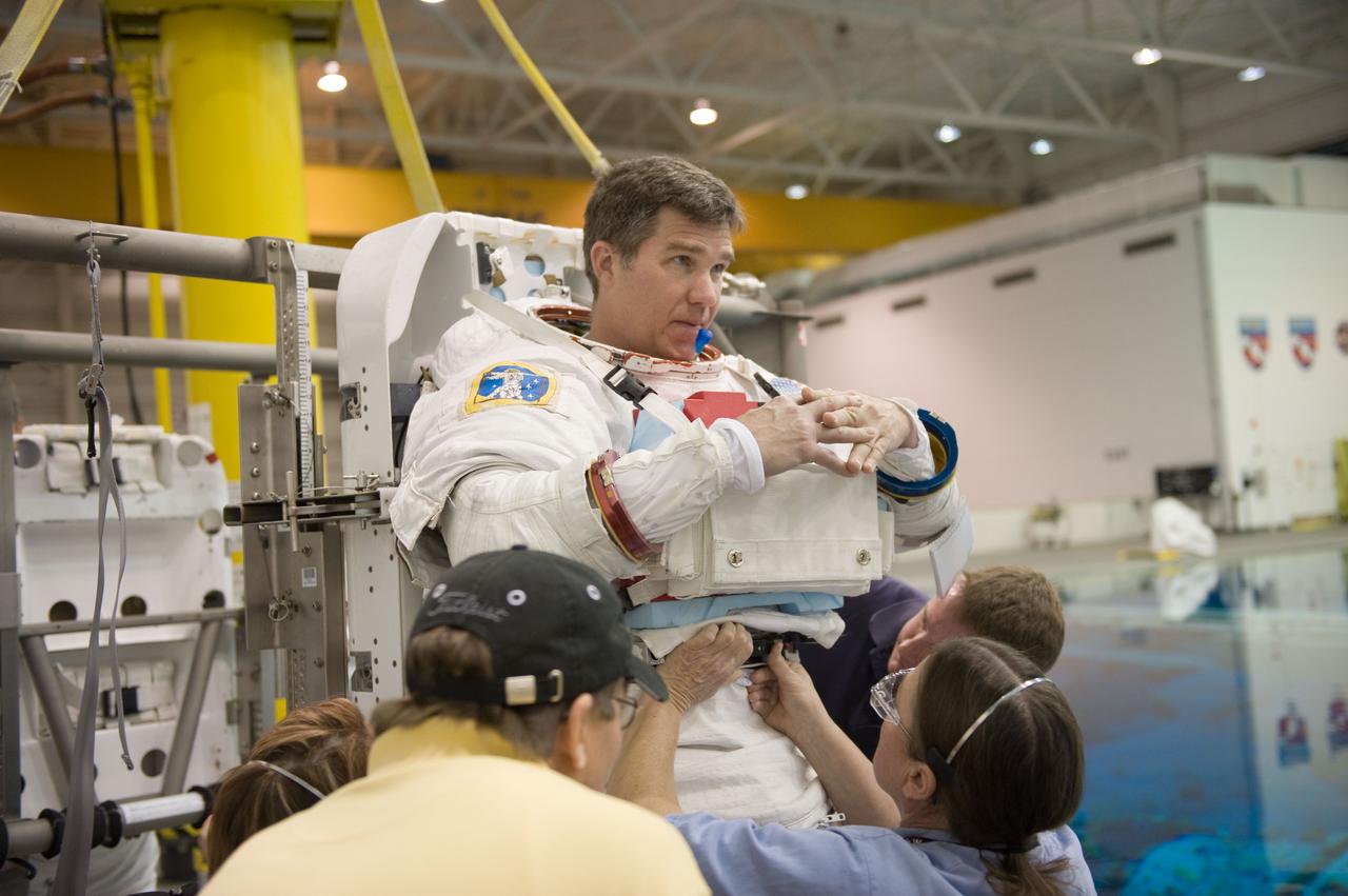 JSC2010-E-019602 (8 Feb. 2010) --- NASA astronaut Steve Bowen, STS-132 mission specialist, gets help in the donning of a training version of his Extravehicular Mobility Unit (EMU) spacesuit in preparation for a spacewalk training session in the waters of the Neutral Buoyancy Laboratory (NBL) near NASA's Johnson Space Center.