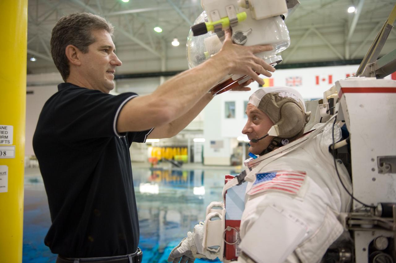 JSC2010-E-019613 (8 Feb. 2010) --- NASA astronaut Garrett Reisman, STS-132 mission specialist, dons a training version of his Extravehicular Mobility Unit (EMU) spacesuit in preparation for a spacewalk training session in the waters of the Neutral Buoyancy Laboratory (NBL) near NASA's Johnson Space Center. Astronaut Michael Good, mission specialist, assisted Reisman.