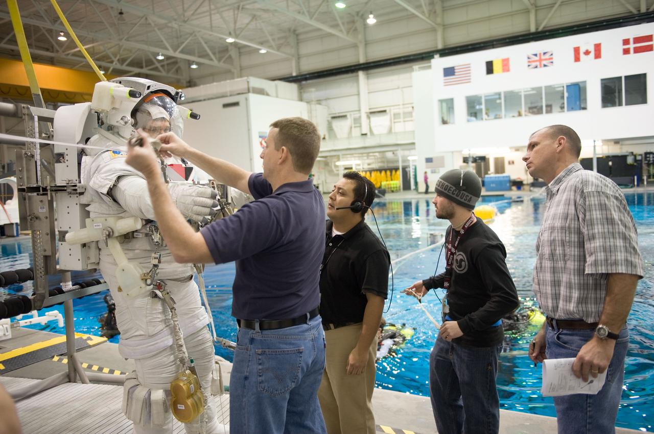 JSC2010-E-019625 (8 Feb. 2010) --- NASA astronaut Steve Bowen, STS-132 mission specialist, gets help in the donning of a training version of his Extravehicular Mobility Unit (EMU) spacesuit in preparation for a spacewalk training session in the waters of the Neutral Buoyancy Laboratory (NBL) near NASA's Johnson Space Center. Astronaut Ken Ham, commander, assisted Bowen. Astronaut Tony Antonelli, pilot, is at far right.
