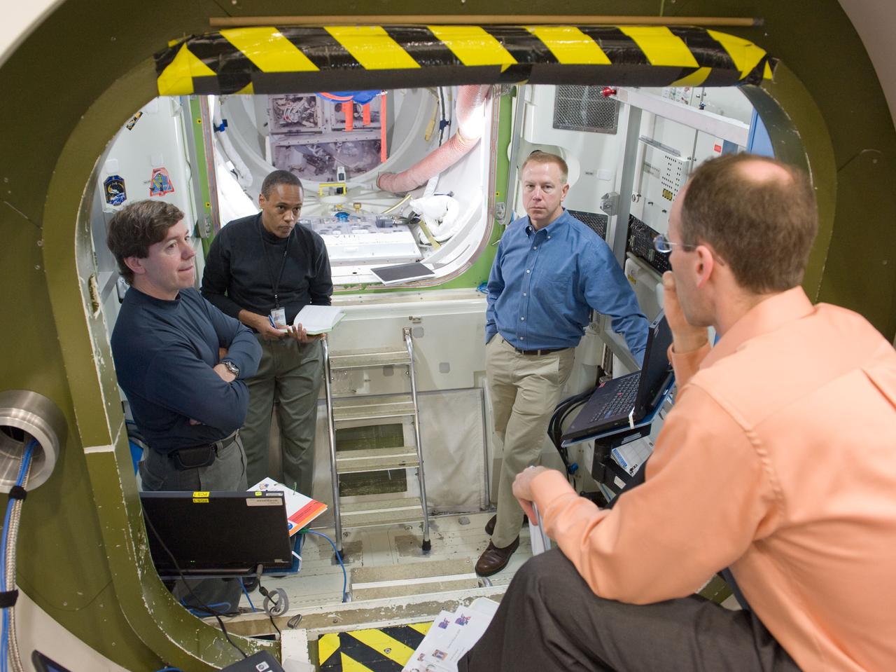JSC2010-E-020704 (10 Feb. 2010) --- NASA astronauts Michael Barratt (left), Alvin Drew and Tim Kopra (right background), all STS-133 mission specialists, participate in a training session in an International Space Station mock-up/trainer in the Space Vehicle Mock-up Facility at NASA's Johnson Space Center.