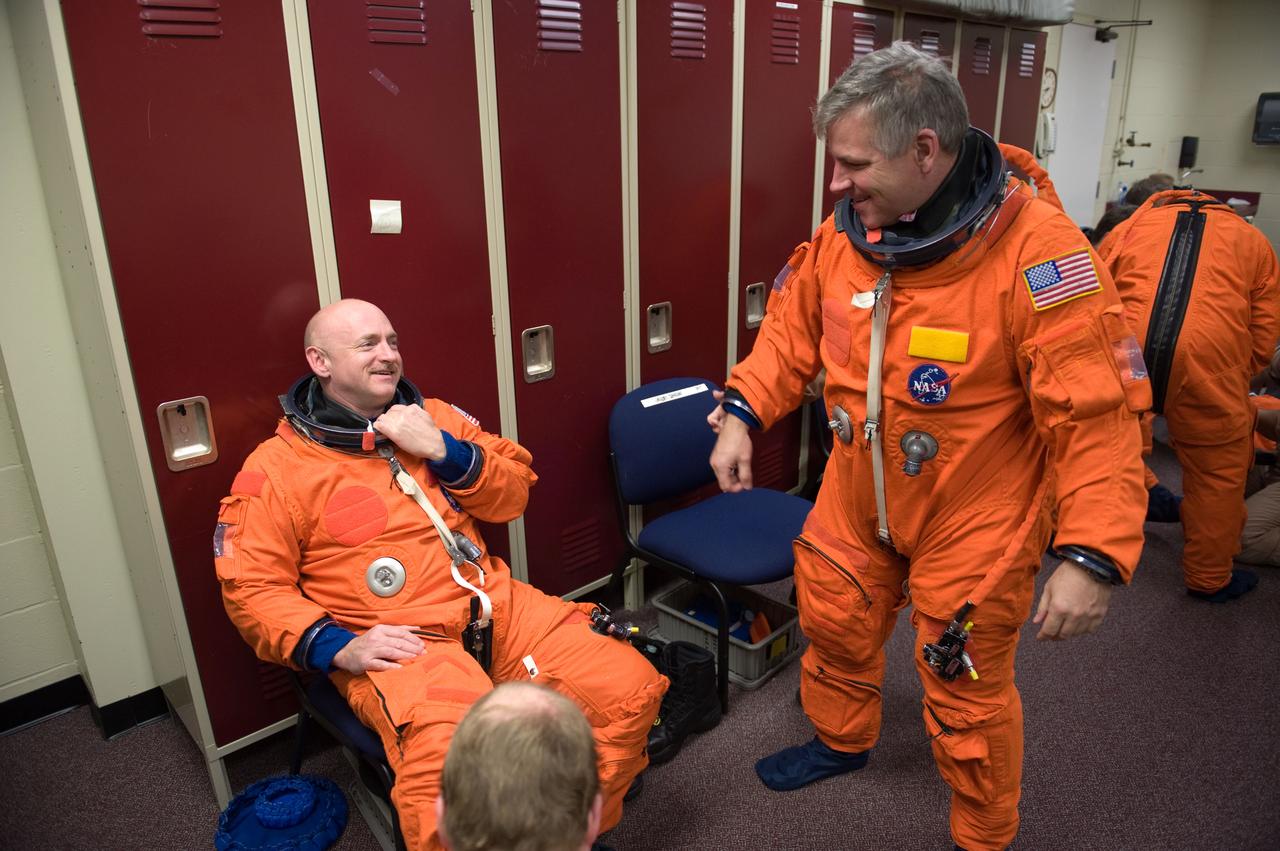 JSC2010-E-024579 (11 Feb. 2010) --- NASA astronauts Mark Kelly (seated), STS-134 commander; and Gregory H. Johnson, pilot, attired in training versions of their shuttle launch and entry suits, prepare for a training session in the Space Vehicle Mock-up Facility at NASA's Johnson Space Center.