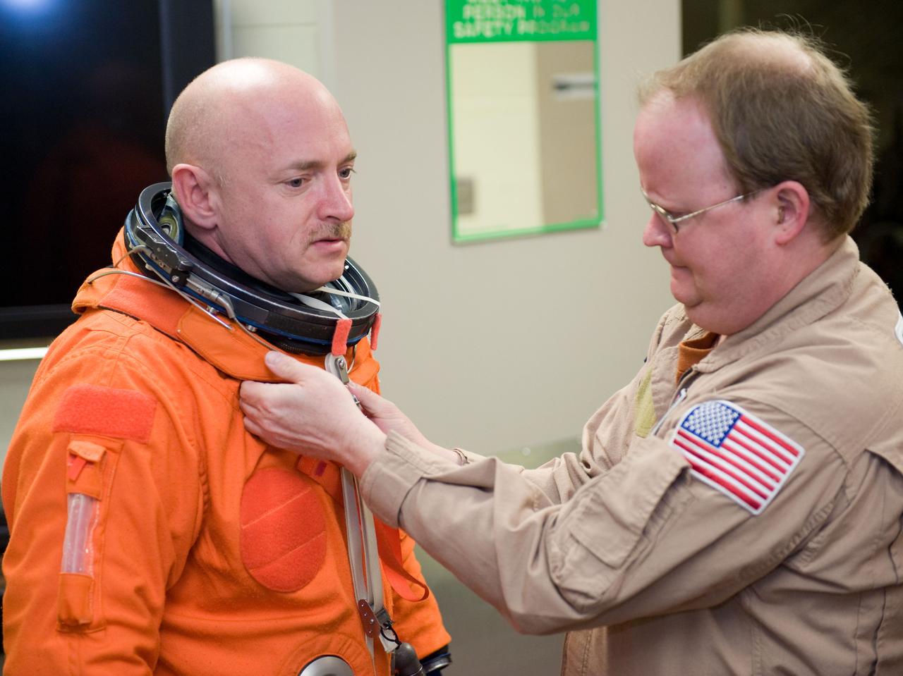 JSC2010-E-024585 (11 Feb. 2010) --- NASA astronaut Mark Kelly, STS-134 commander, dons a training version of his shuttle launch and entry suit in preparation for a training session in the Space Vehicle Mock-up Facility at NASA's Johnson Space Center. United Space Alliance suit technician Daniel Palmer assisted Kelly.