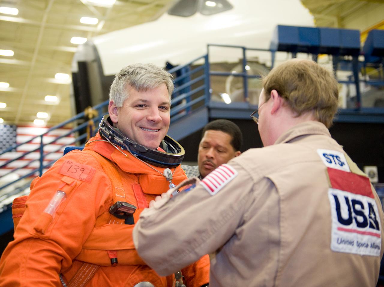 JSC2010-E-024590 (11 Feb. 2010) --- NASA astronaut Gregory H. Johnson, STS-134 pilot, dons a training version of his shuttle launch and entry suit in preparation for a training session in the Space Vehicle Mock-up Facility at NASA's Johnson Space Center. United Space Alliance suit technicians Daniel Palmer (right foreground) and George Brittingham assisted Johnson.