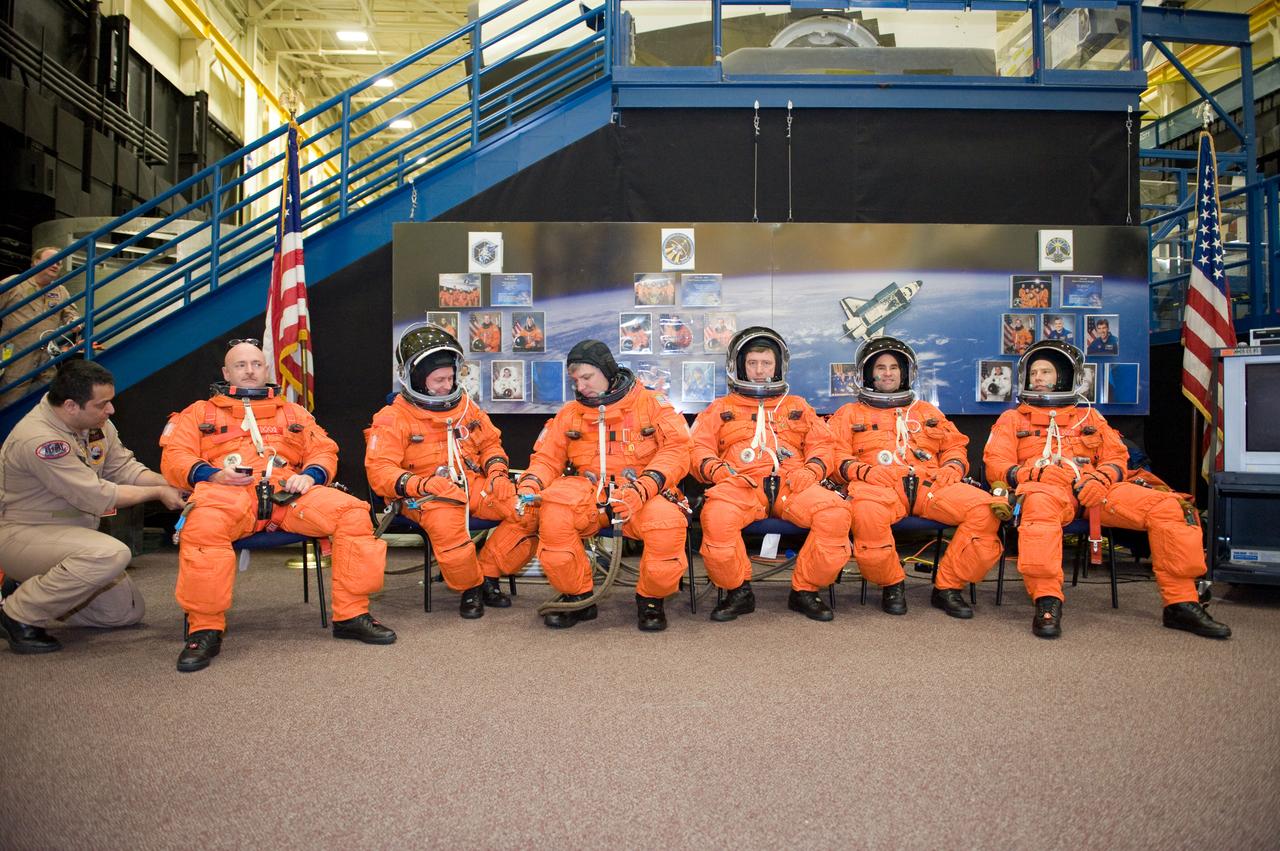 JSC2010-E-024602 (11 Feb. 2010) --- The STS-134 crew members, attired in training versions of their shuttle launch and entry suits, await the start of a training session in the crew compartment trainer (CCT-2) in the Space Vehicle Mockup Facility at NASA's Johnson Space Center. Pictured from the left are NASA astronauts Mark Kelly, commander; Michael Fincke, mission specialist; Gregory H. Johnson, pilot; European Space Agency astronaut Roberto Vittori, NASA astronauts Greg Chamitoff and Andrew Feustel, all mission specialists.
