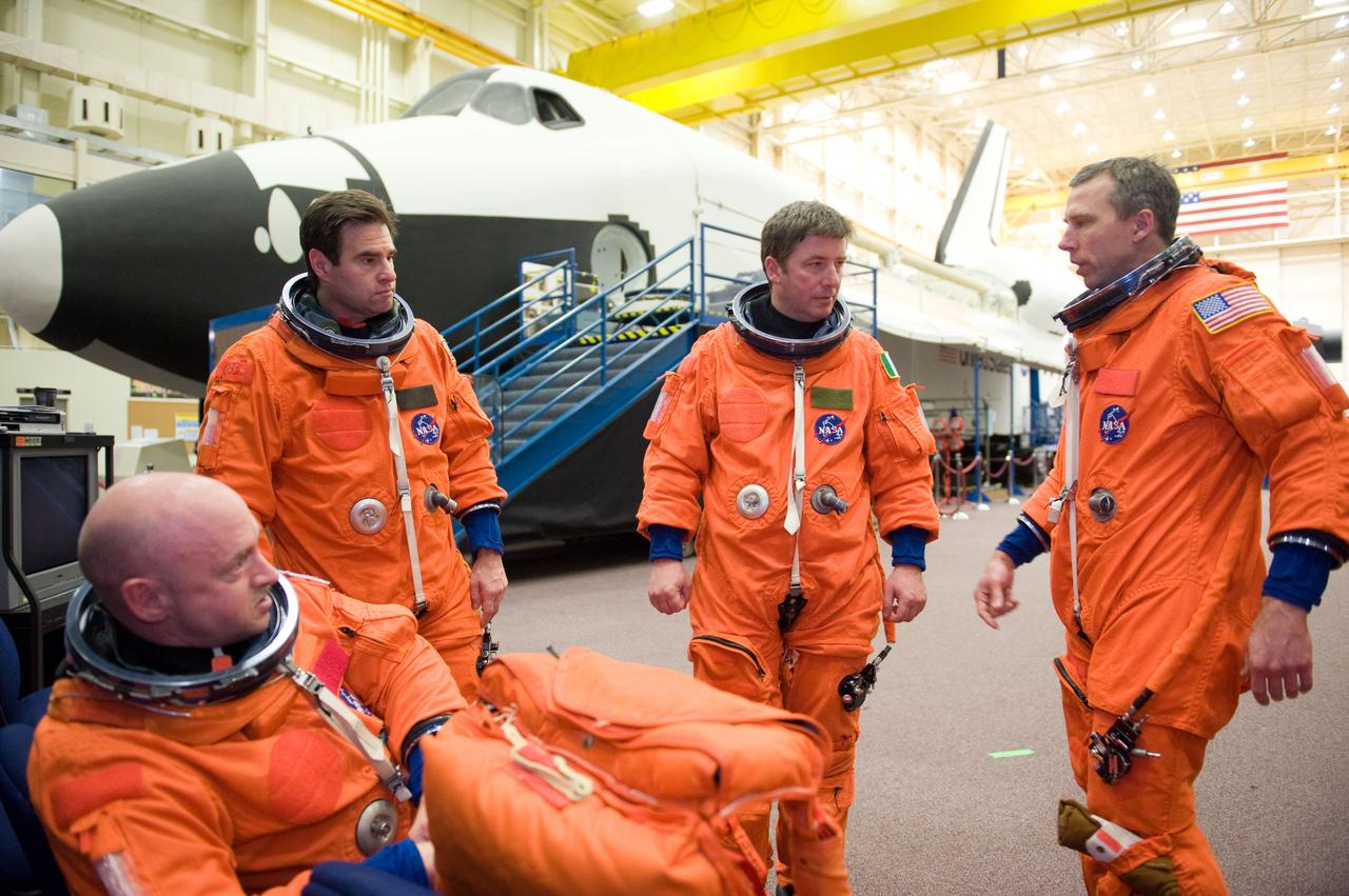 JSC2010-E-024616 (11 Feb. 2010) --- NASA astronauts Mark Kelly (seated), STS-134 commander; Greg Chamitoff (left) and Andrew Feustel (right); along with European Space Agency astronaut Roberto Vittori, all mission specialists, attired in training versions of their shuttle launch and entry suits, await the start of a training session in the crew compartment trainer (CCT-2) in the Space Vehicle Mockup Facility at NASA's Johnson Space Center.