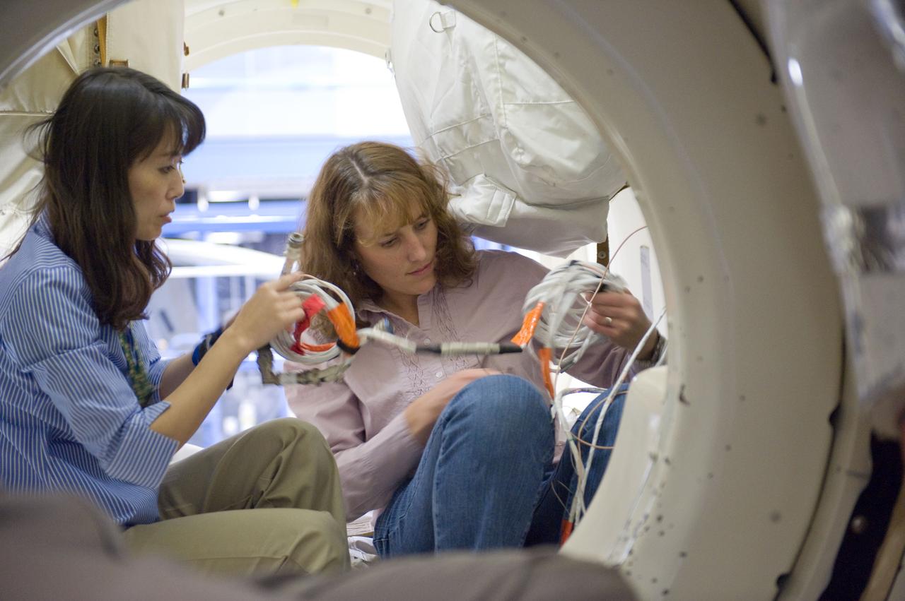 JSC2010-E-024627 (10 Feb. 2010) --- Japan Aerospace Exploration Agency (JAXA) astronaut Naoko Yamazaki (left) and NASA astronaut Dorothy Metcalf-Lindenburger, both STS-131 mission specialists, participate in an ingress/egress timeline training session in a shuttle mock-up in the Space Vehicle Mock-up Facility at NASA's Johnson Space Center.