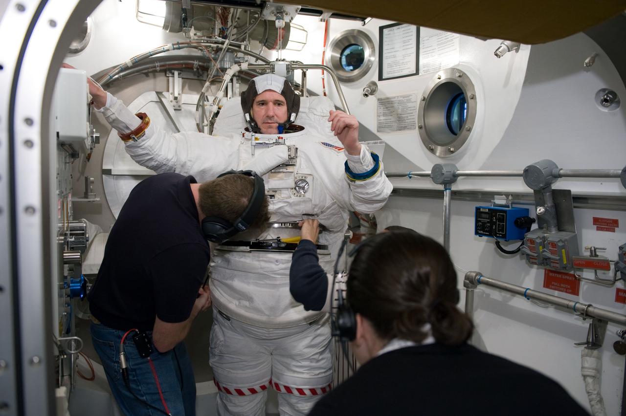 JSC2010-E-026881 (26 Feb. 2010) --- NASA astronaut Michael Good, STS-132 mission specialist, participates in an Extravehicular Mobility Unit (EMU) spacesuit fit check in the Space Station Airlock Test Article (SSATA) in the Crew Systems Laboratory at NASA's Johnson Space Center. Astronaut Ken Ham (left), commander, assisted Good.
